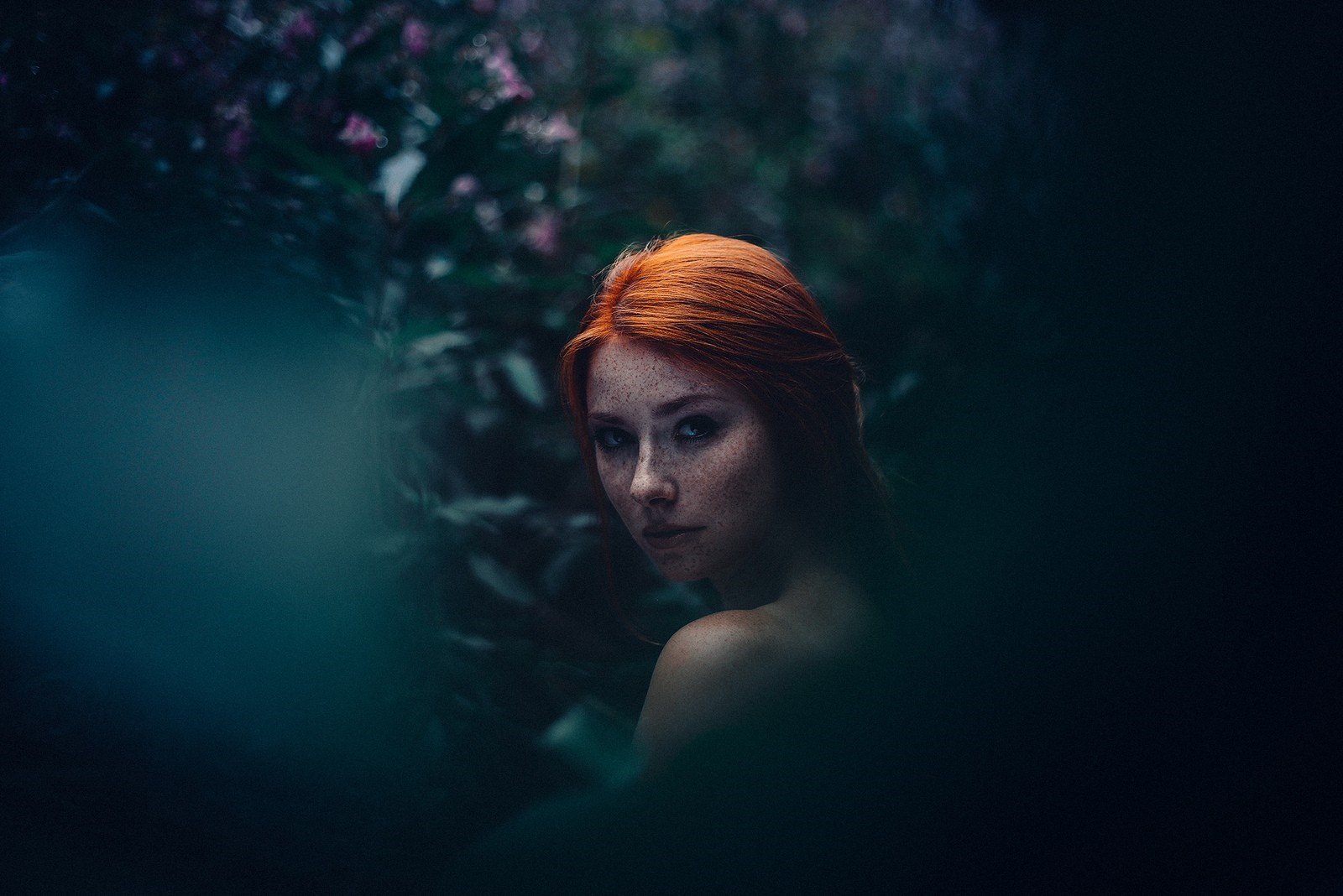 Redhead woman with freckles in dark foliage HD Wallpaper