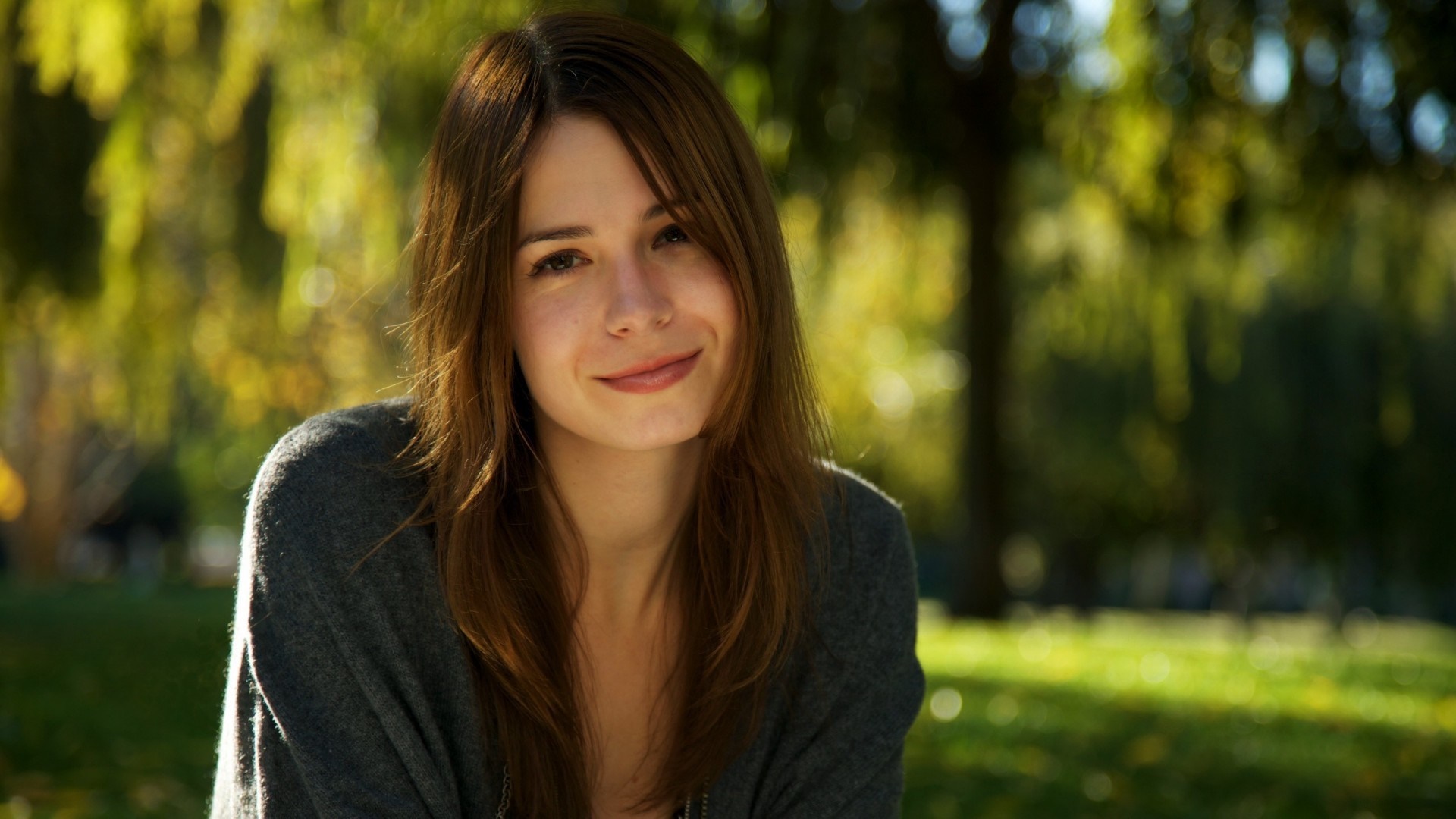 Woman smiling outdoors in sunlight HD Wallpaper