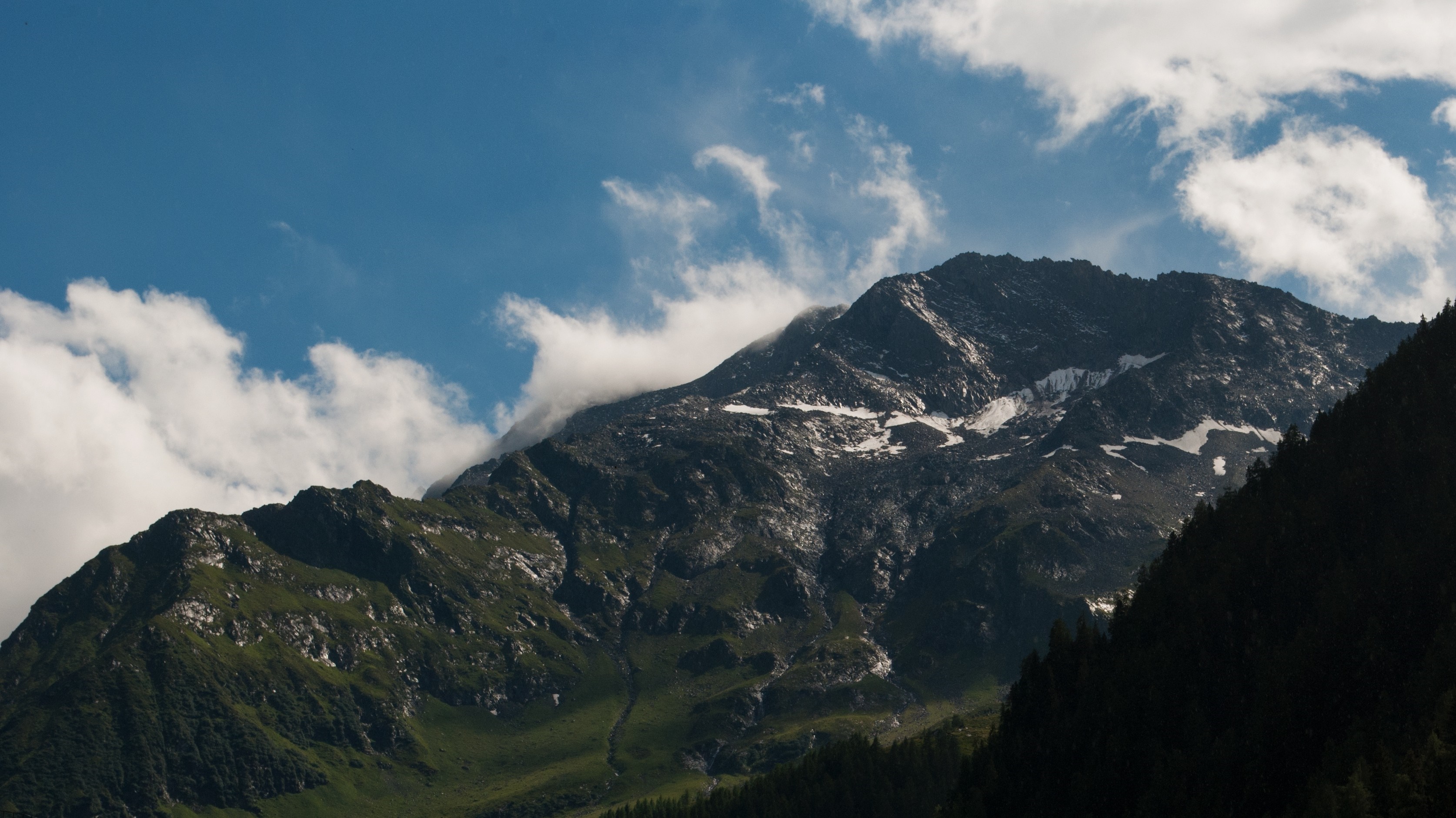 Snow-capped mountain peak under a blue sky with clouds HD Wallpaper