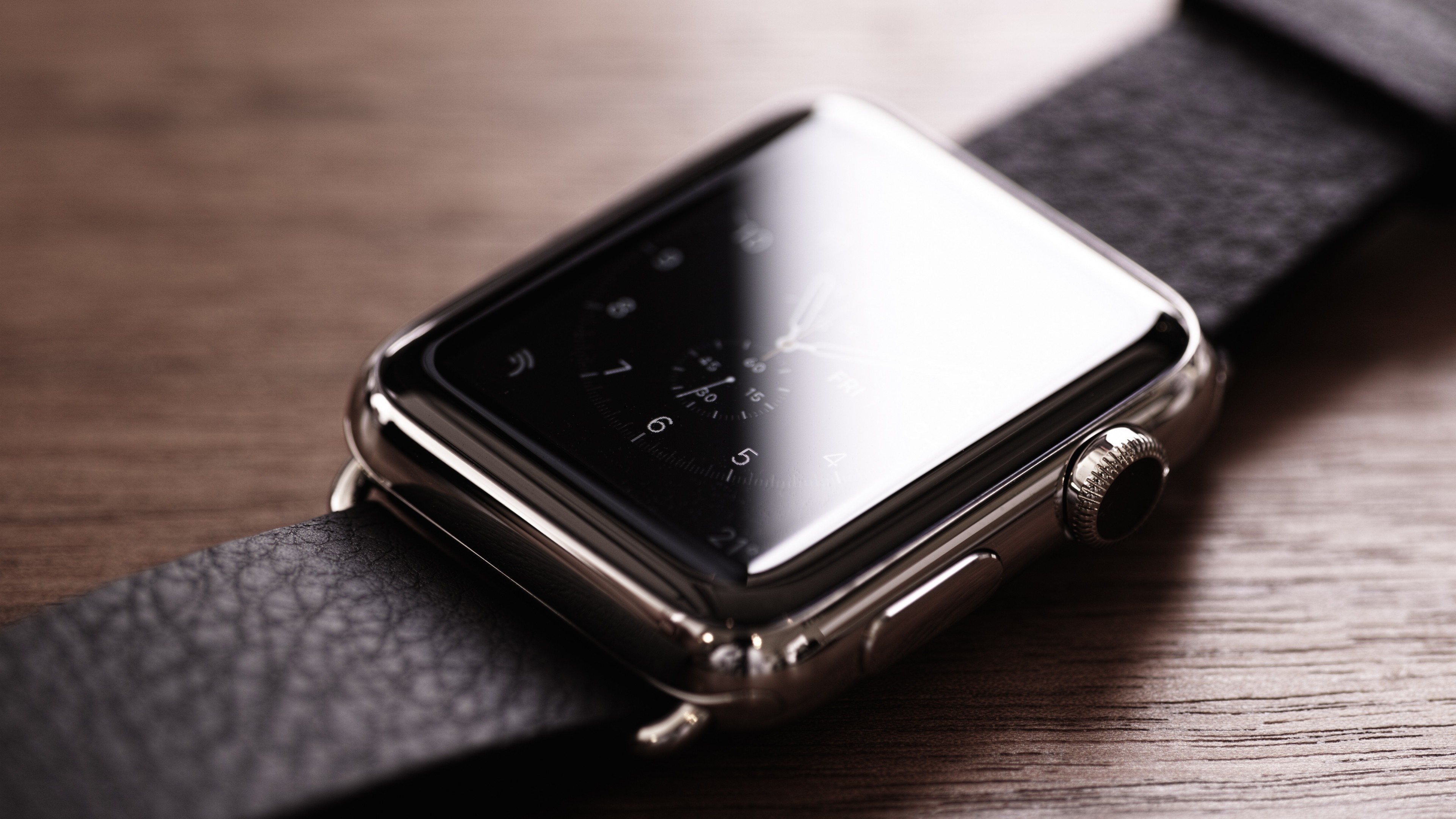 Apple Watch with black leather band on wooden surface HD Wallpaper