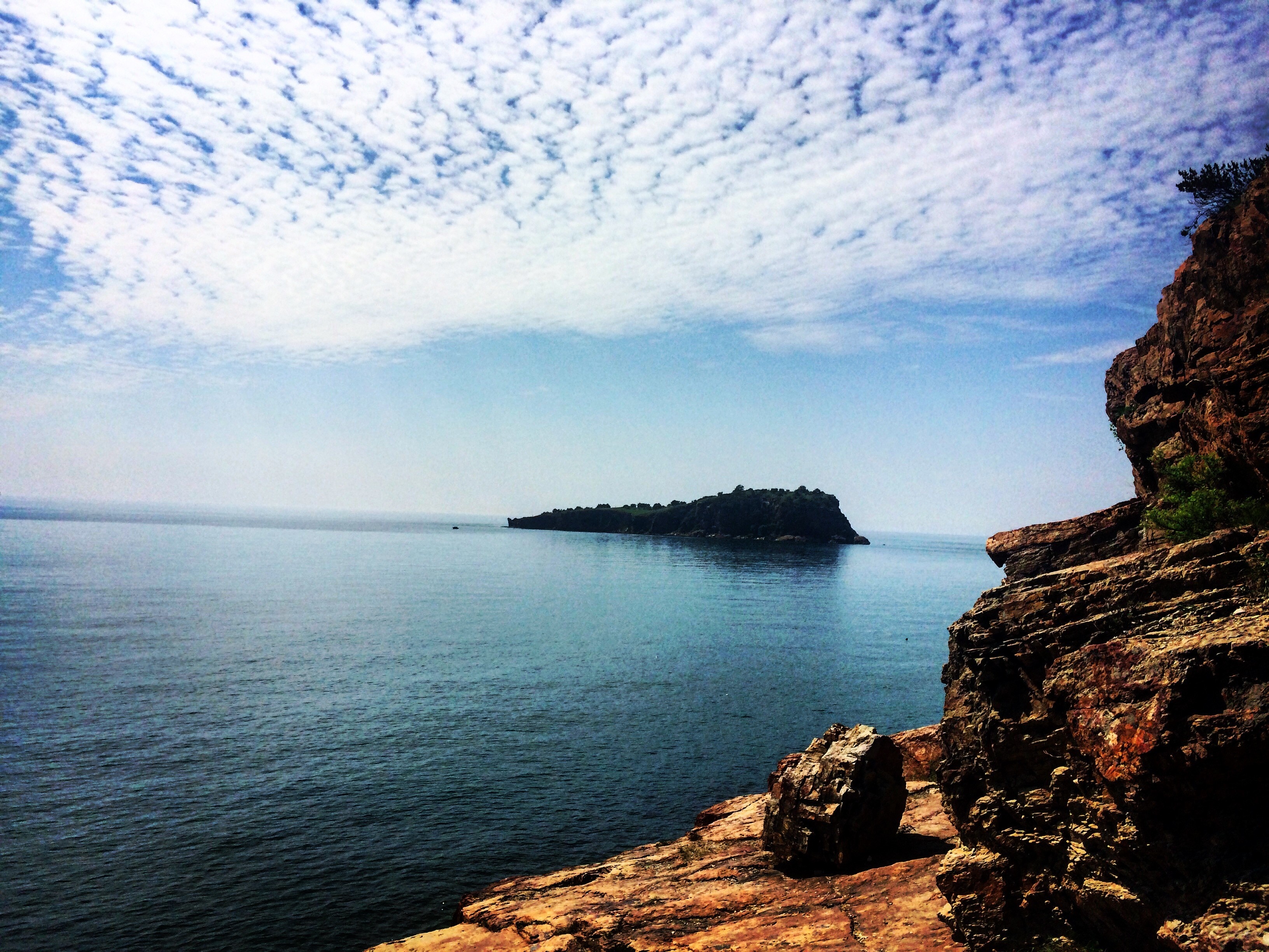 Island in the sea with rocky cliffs and clouds HD Wallpaper