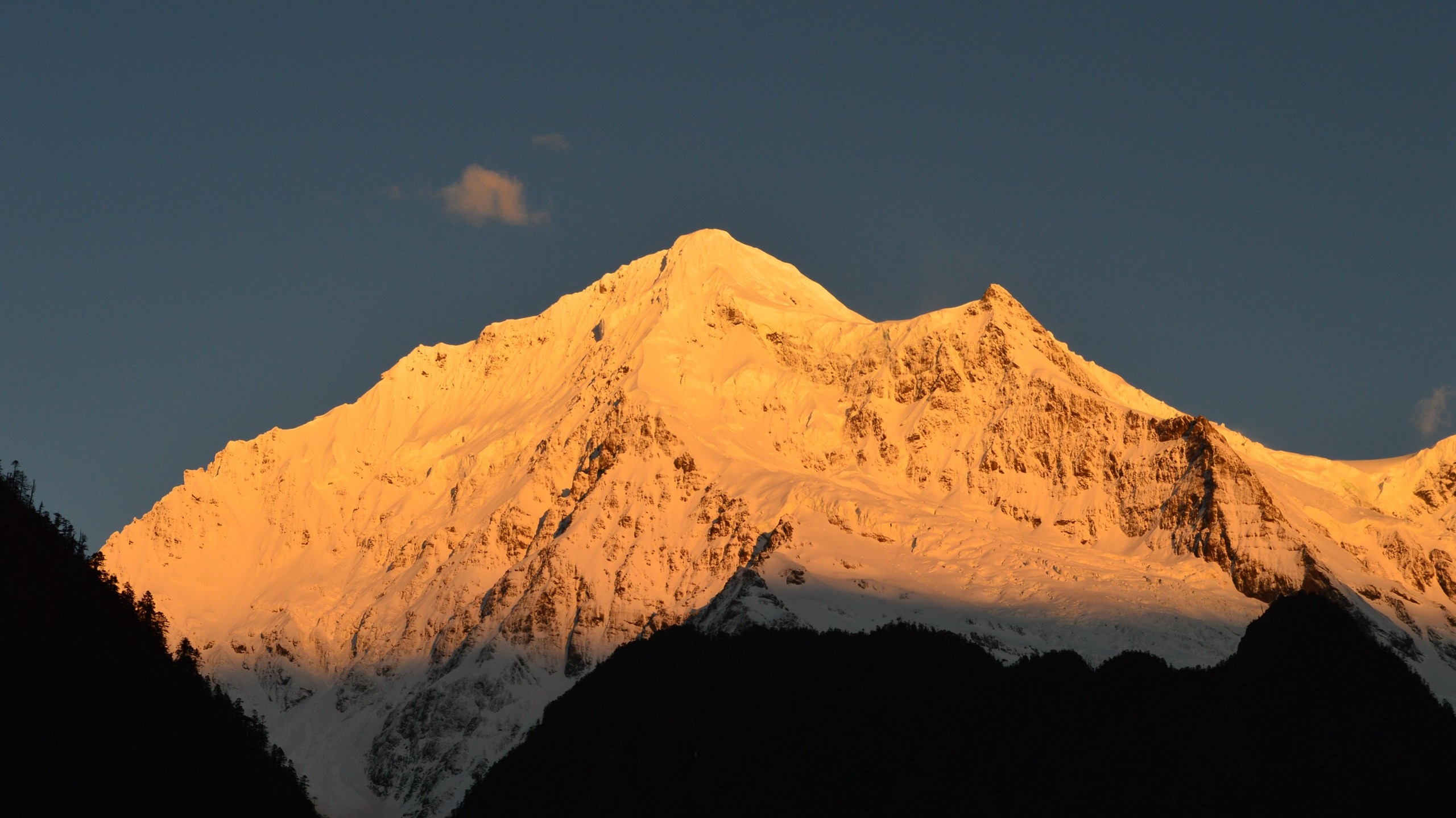 Snow-capped mountain peak illuminated by golden sunrise HD Wallpaper