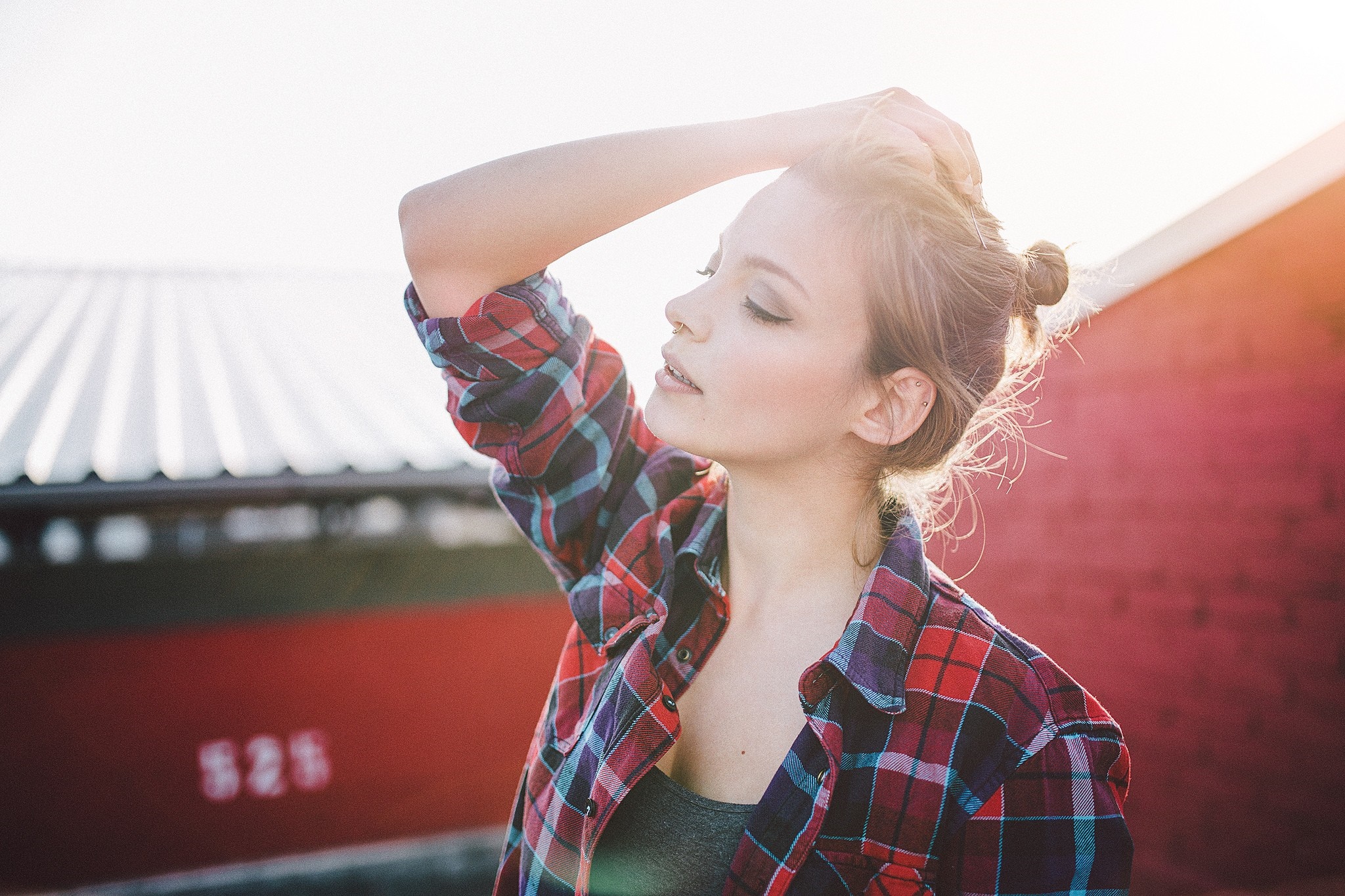 Woman with hand on head wearing plaid shirt on rooftops HD Wallpaper