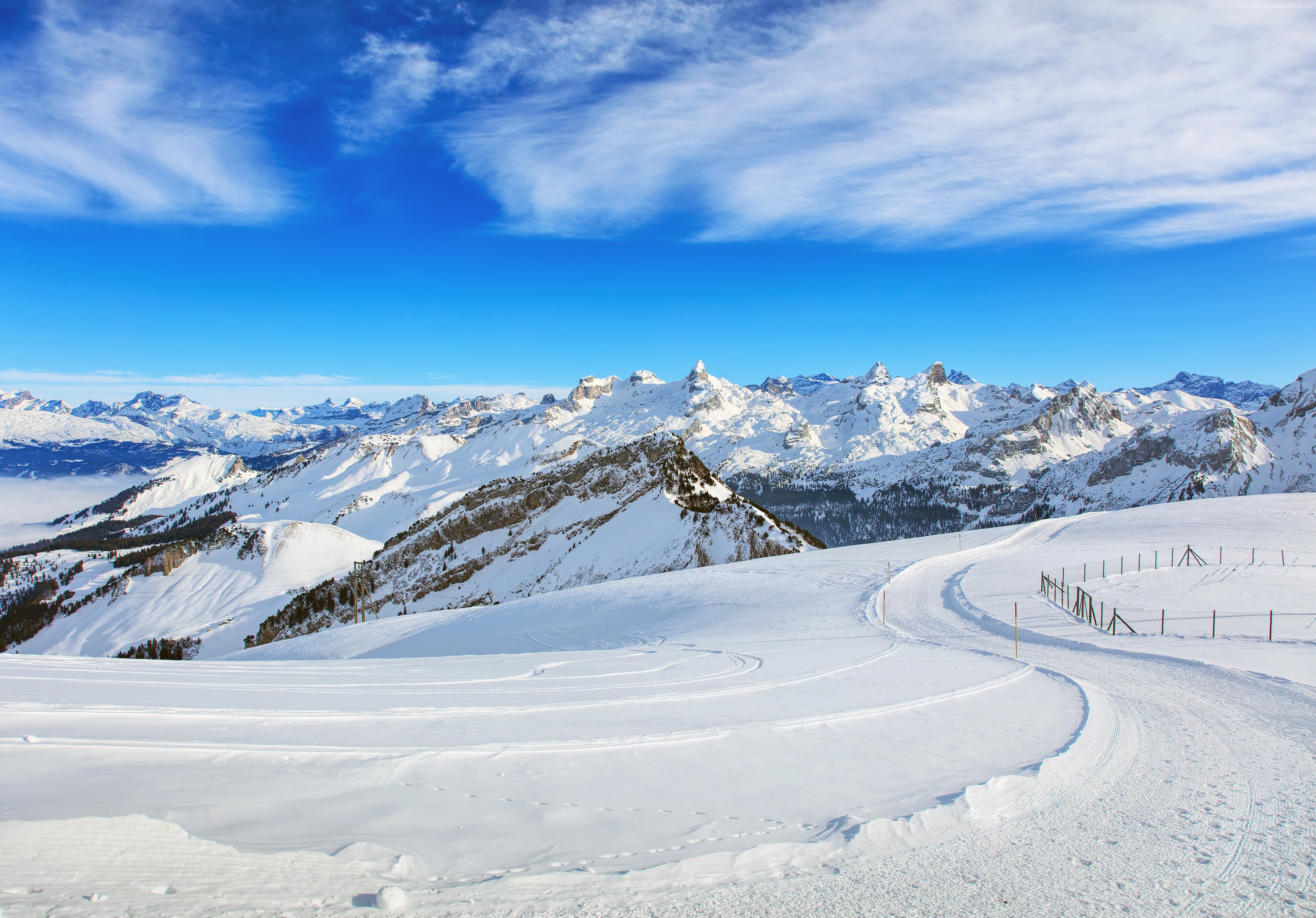 Snowy mountains and ski slope under blue sky with clouds HD Wallpaper