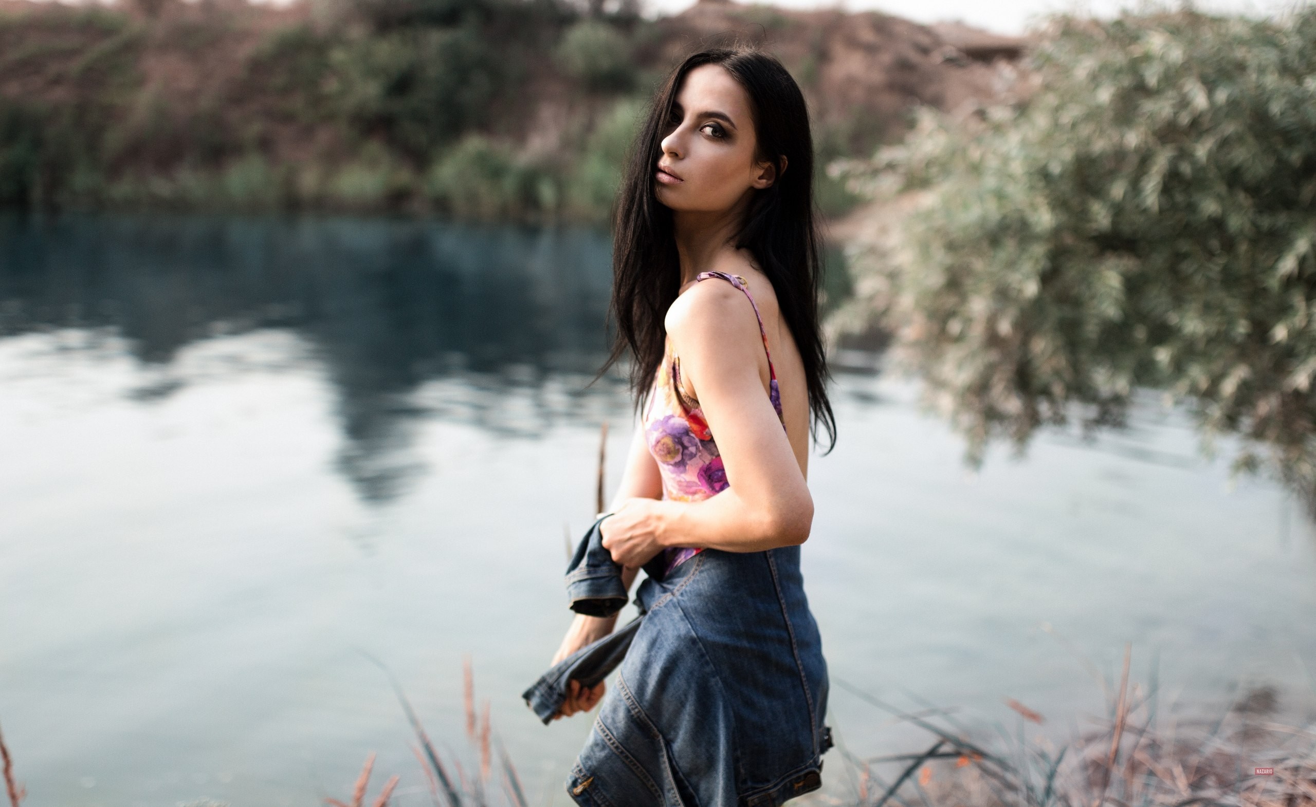Woman in floral dress and denim jacket by a lake HD Wallpaper