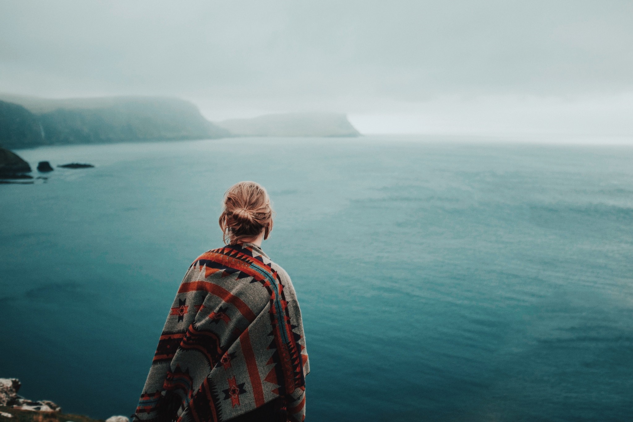 Woman in poncho overlooking the sea HD Wallpaper