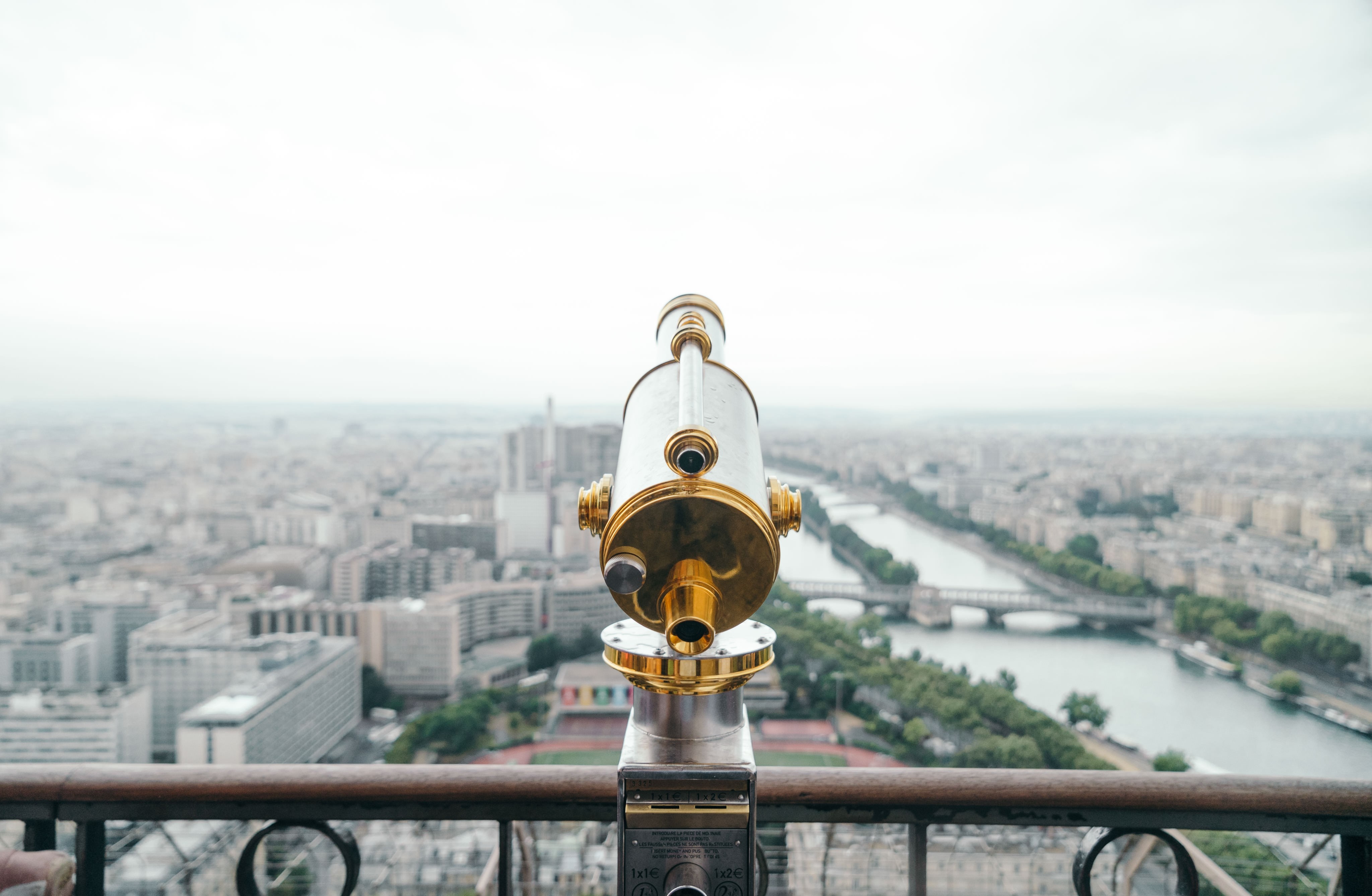 Telescope overlooking a cityscape with a river HD Wallpaper