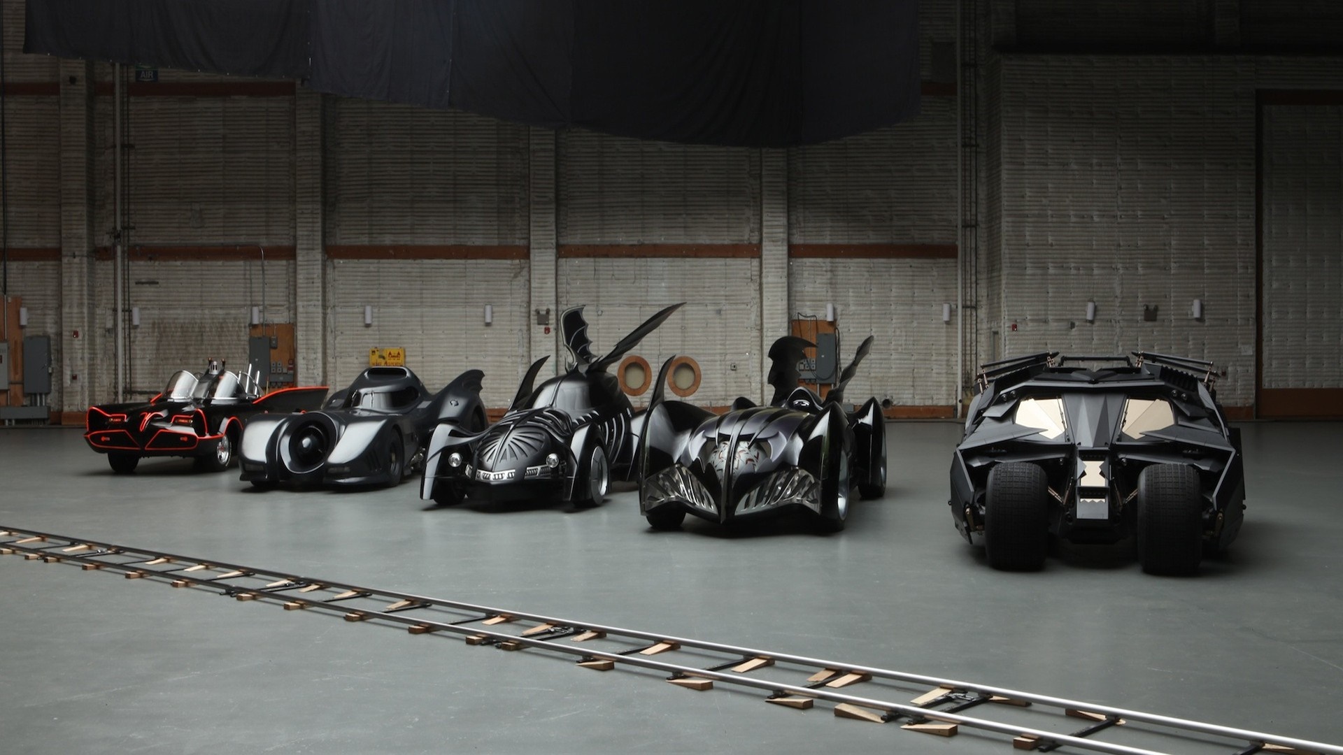 Collection of Iconic Batmobile Cars in Hangar HD Wallpaper