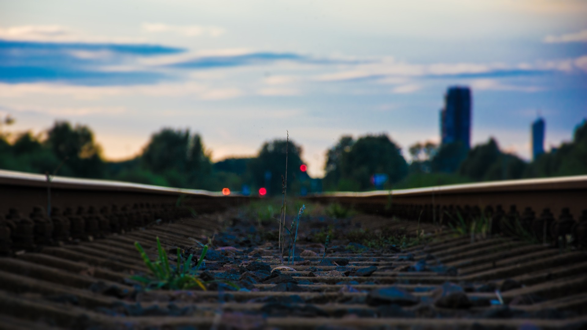 Railway tracks at sunset with city skyline HD Wallpaper