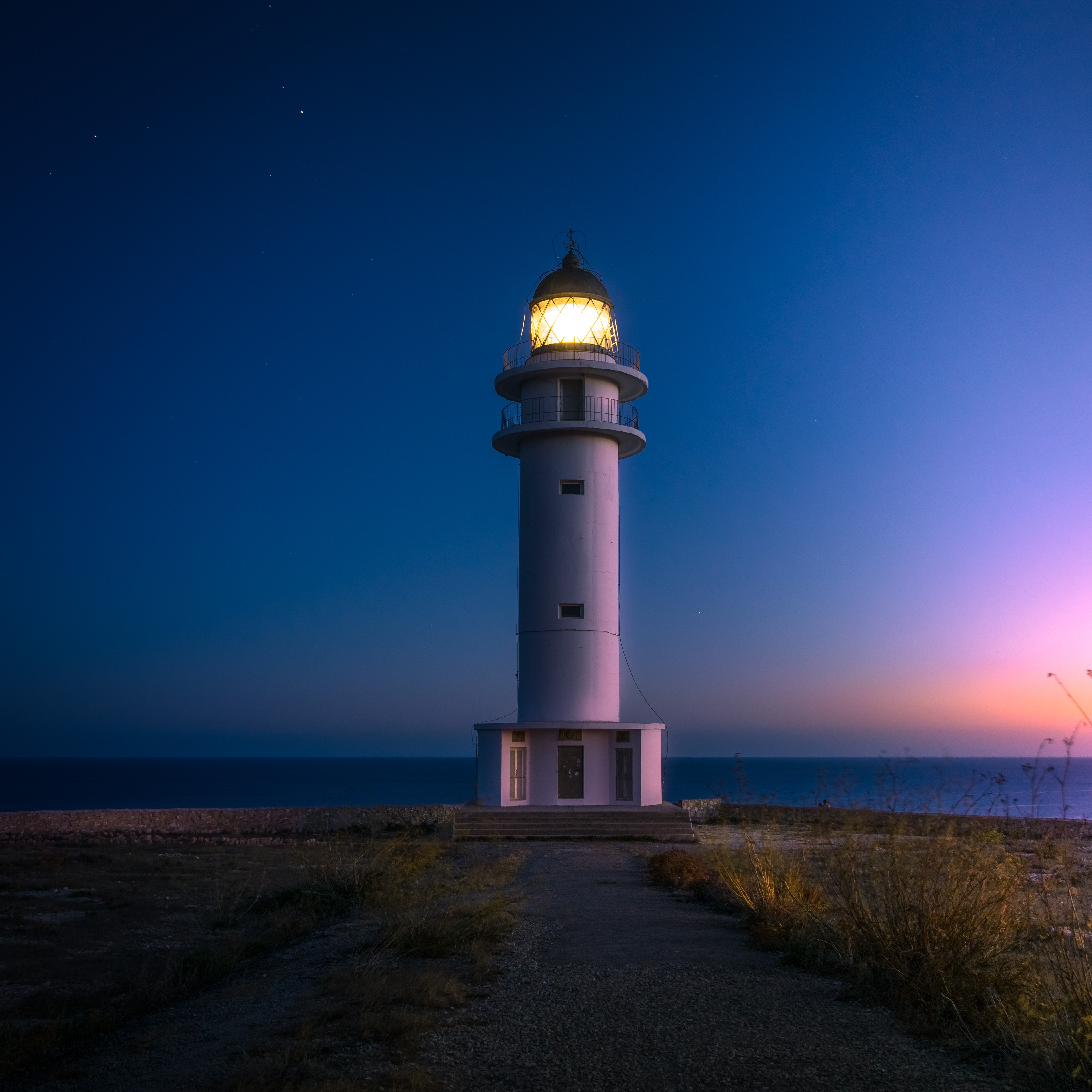 Lighthouse on a rocky coast at dusk HD Wallpaper