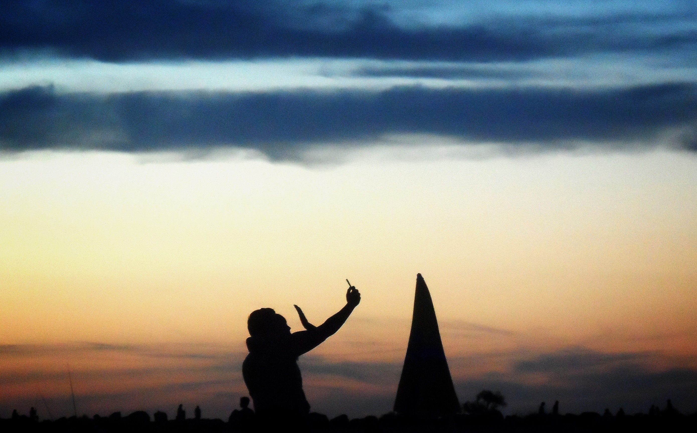 Silhouette of a person taking a selfie at sunset with a sailboat HD Wallpaper