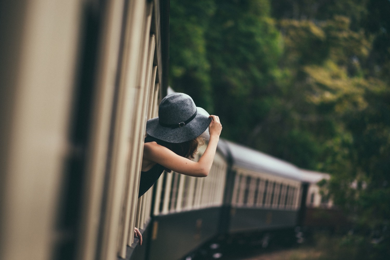 Woman in hat leaning out of a moving train HD Wallpaper