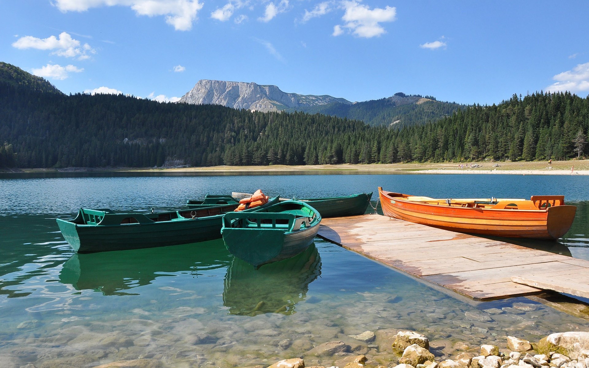 Boats docked on a lake with mountains and forest HD Wallpaper