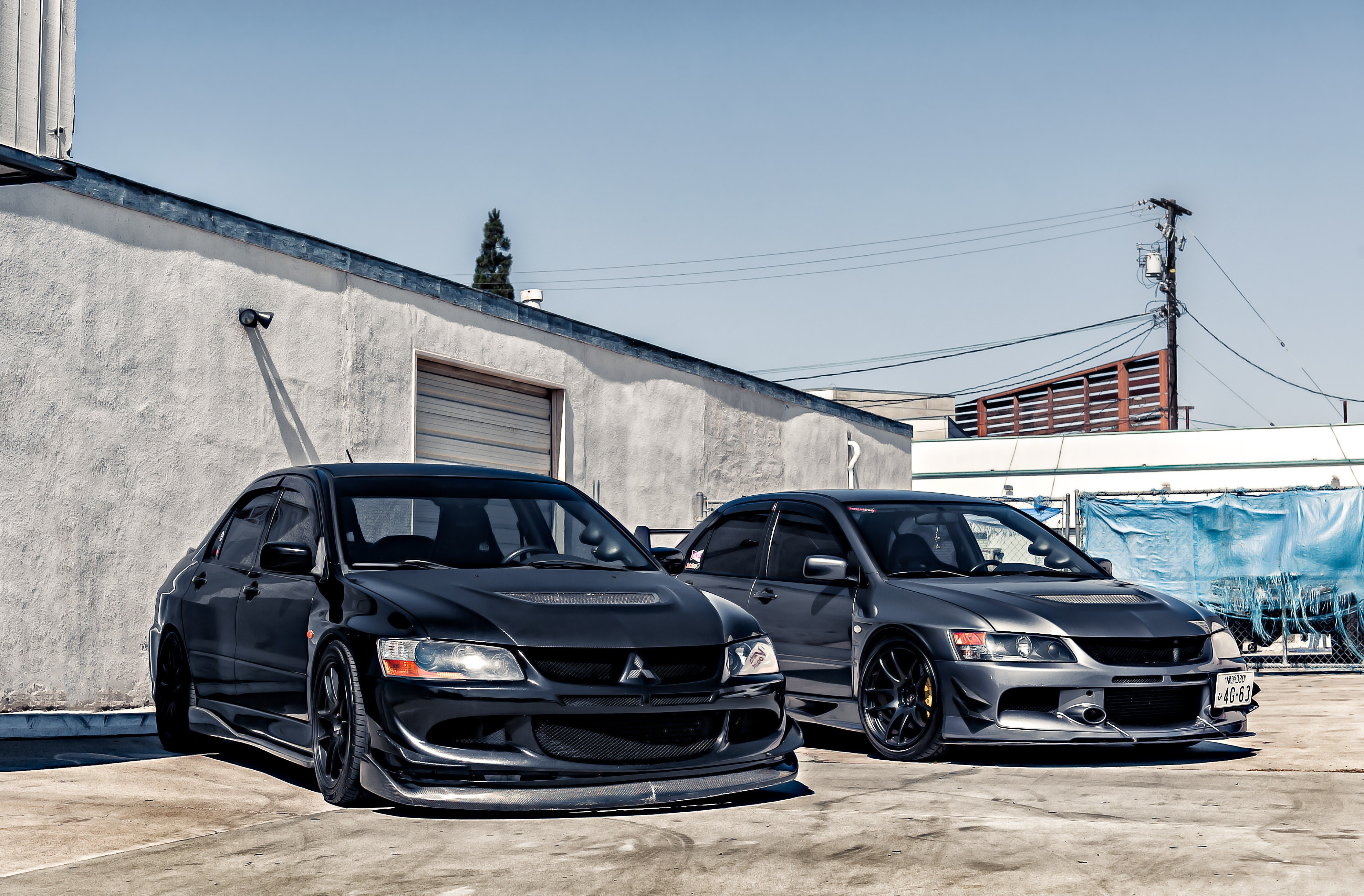 Two Mitsubishi Lancer Evolution cars parked outside a building HD Wallpaper