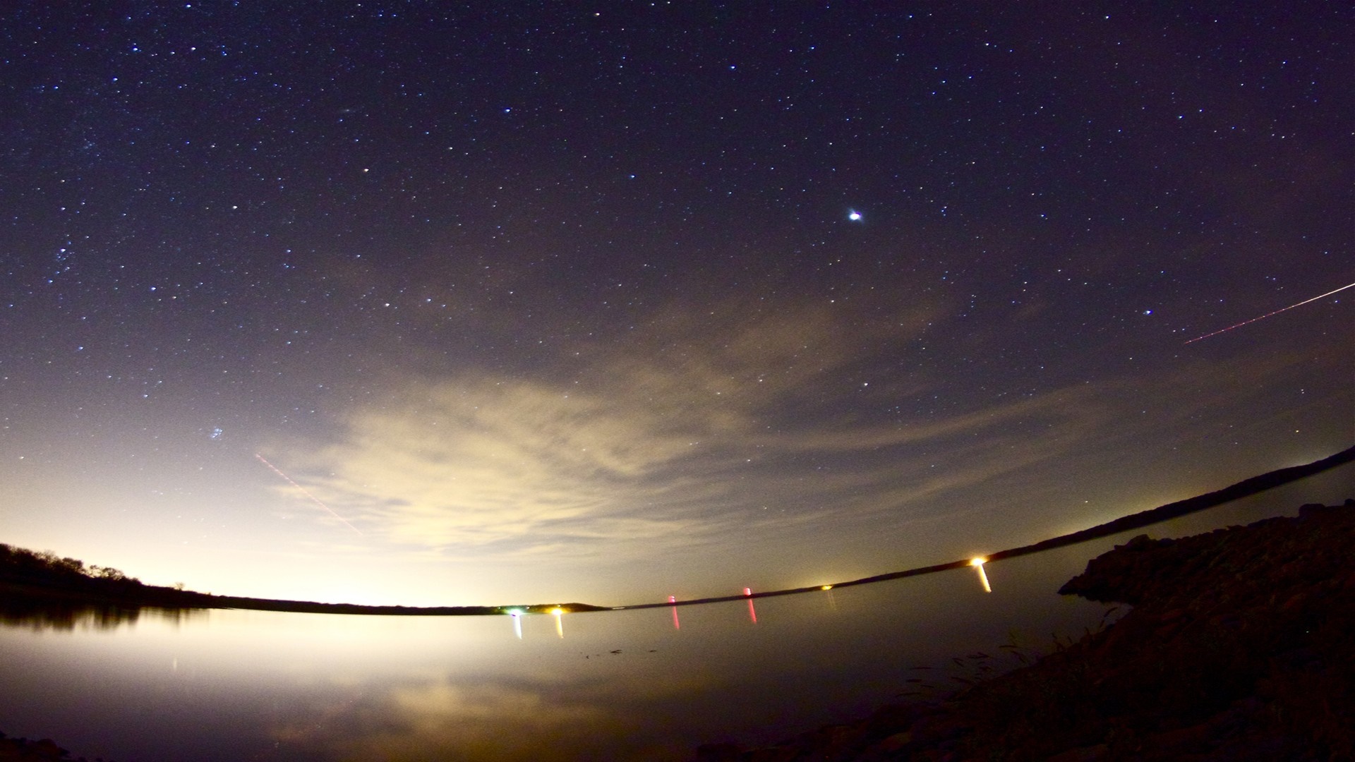Night sky over a lake with stars and lights HD Wallpaper
