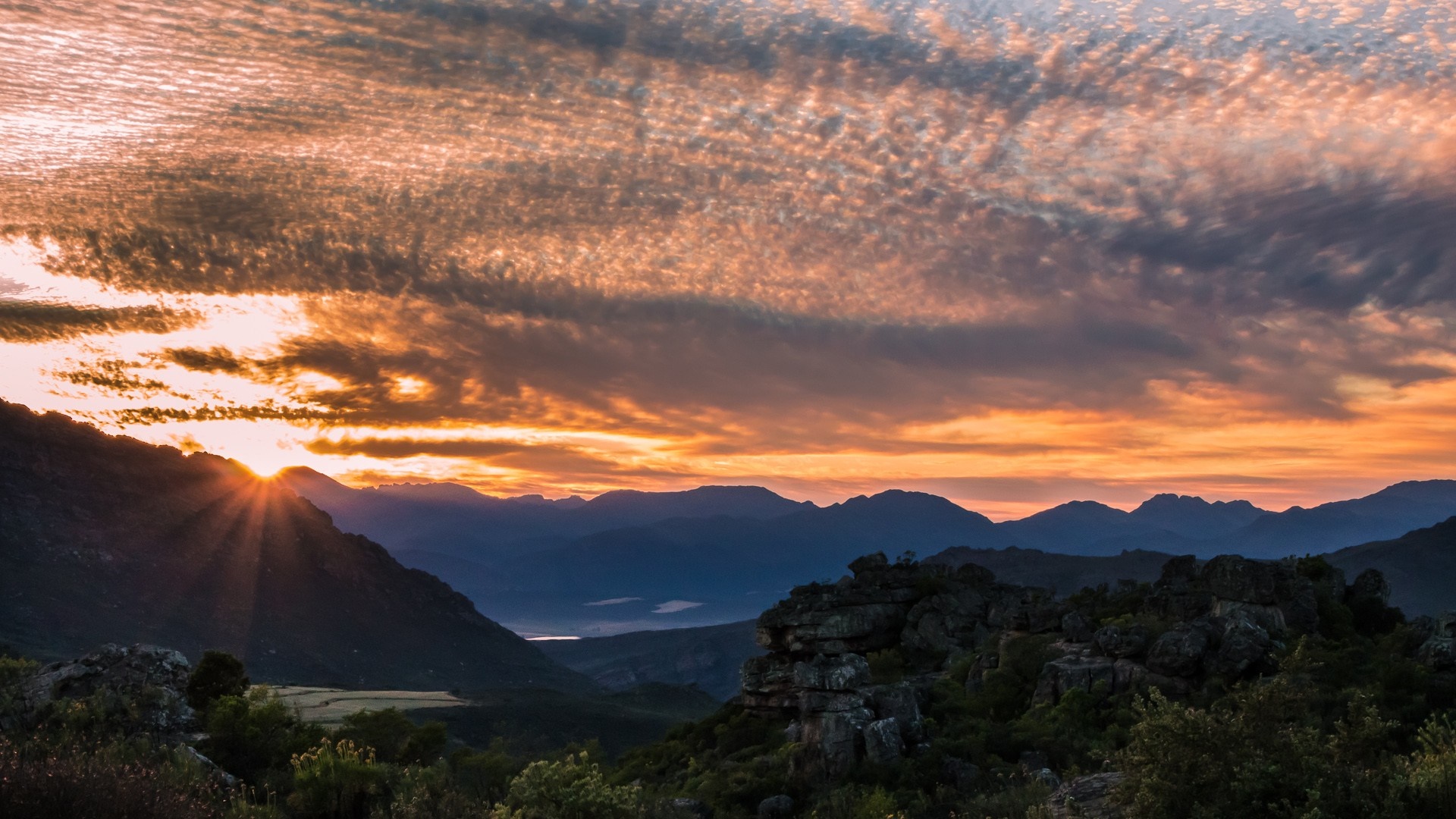 Sunset over a mountain range with dramatic clouds HD Wallpaper