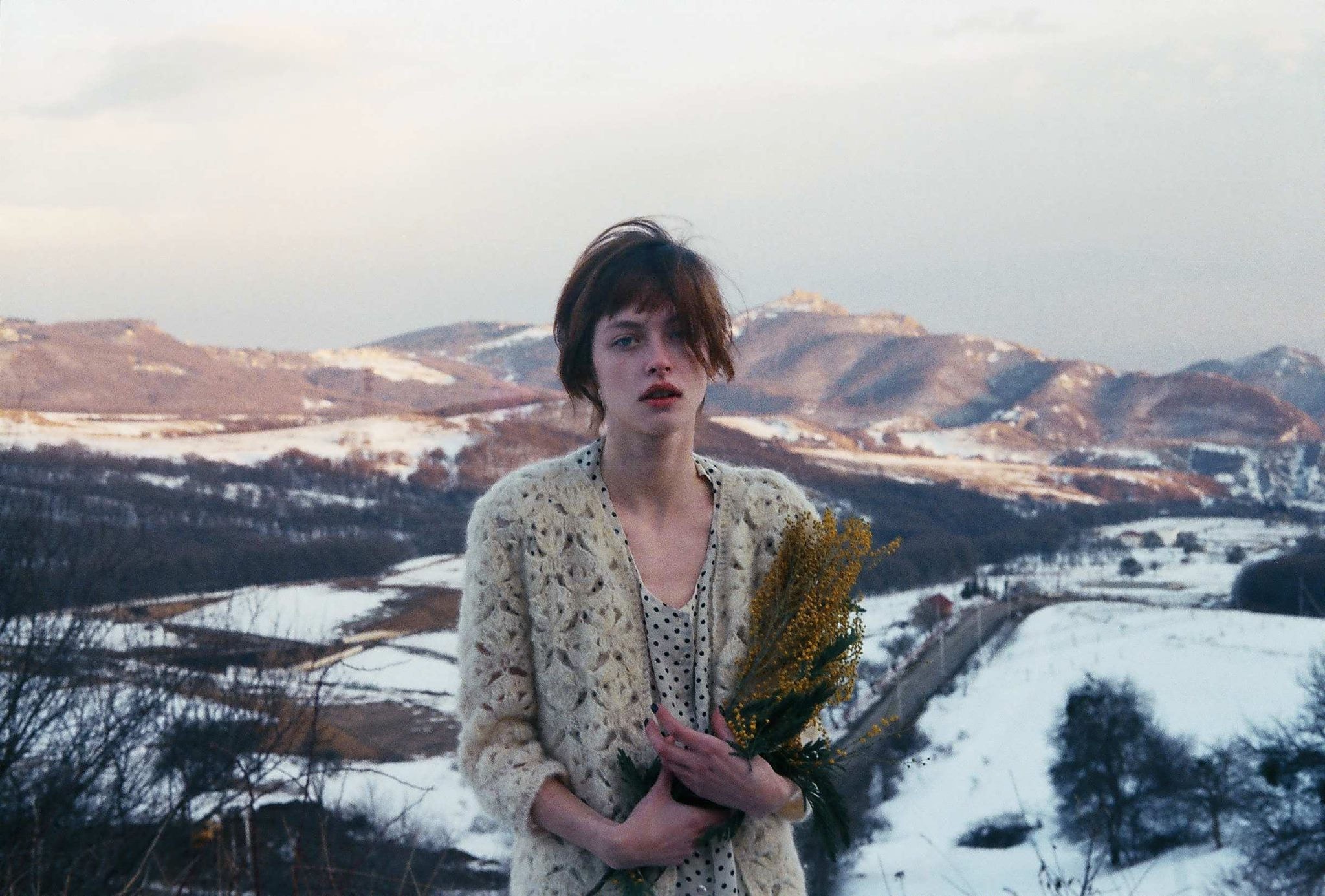 Woman holding flowers in a snowy mountain landscape HD Wallpaper