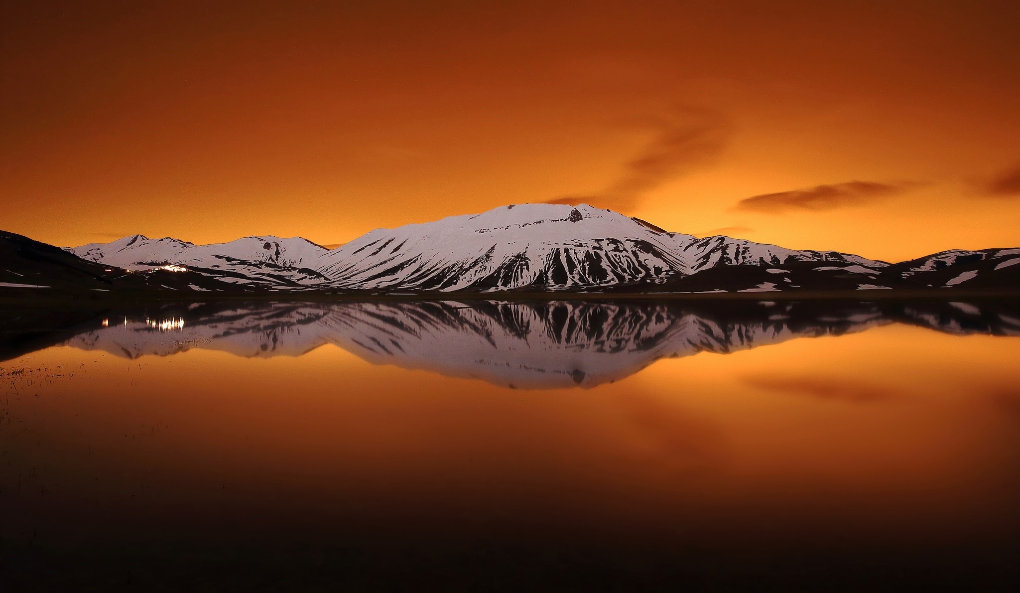 Snowy mountains reflected in a lake at sunset HD Wallpaper