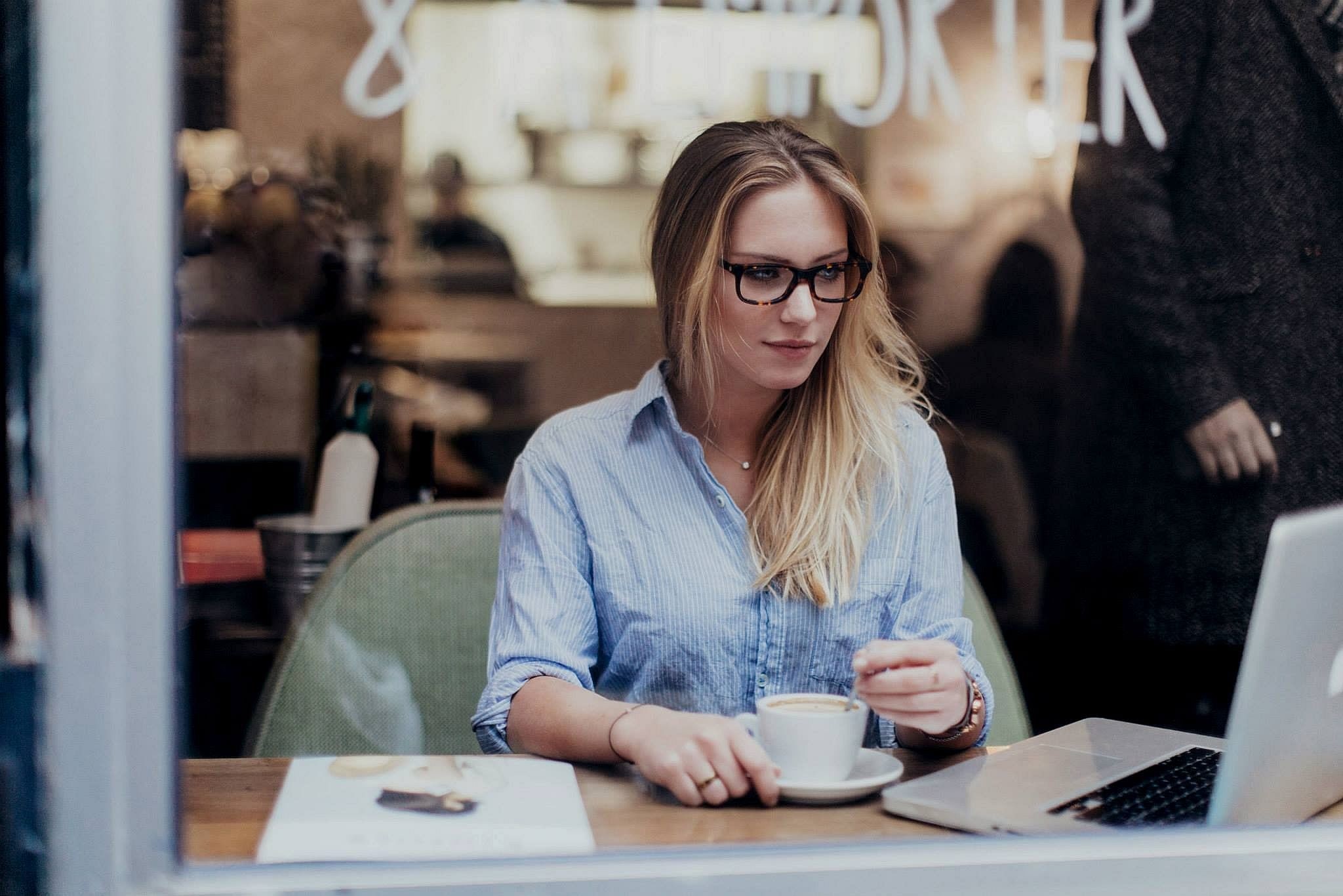 Woman with glasses drinking coffee at a cafe HD Wallpaper