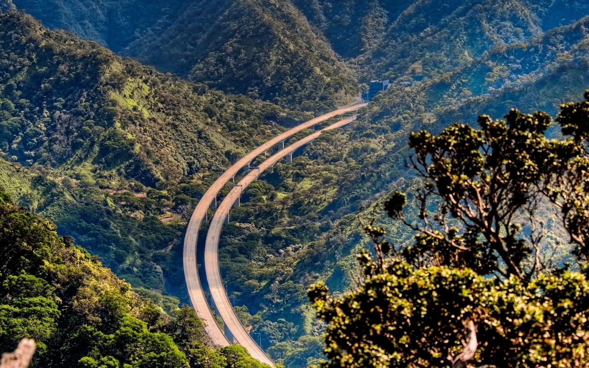 Highway overpass through a lush green mountain valley HD Wallpaper