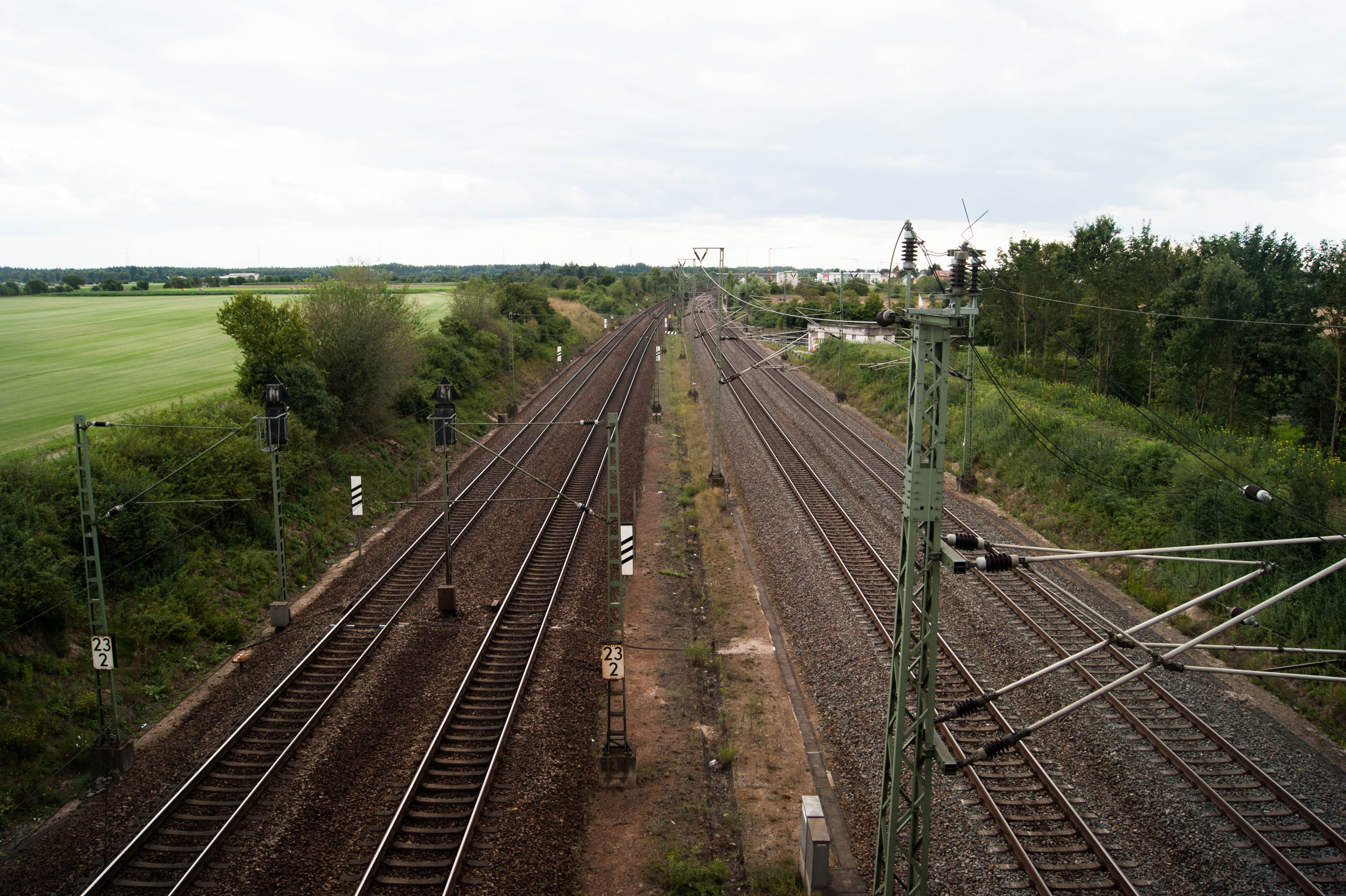 Train tracks through a rural landscape with fields and trees HD Wallpaper