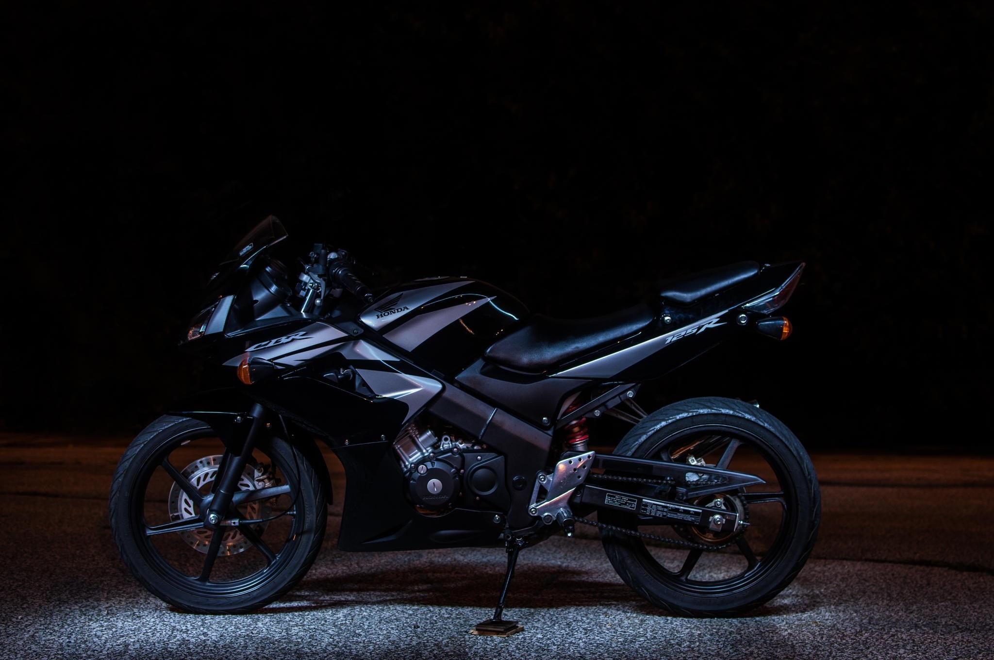 Black Honda CBR125R motorcycle on dark background HD Wallpaper