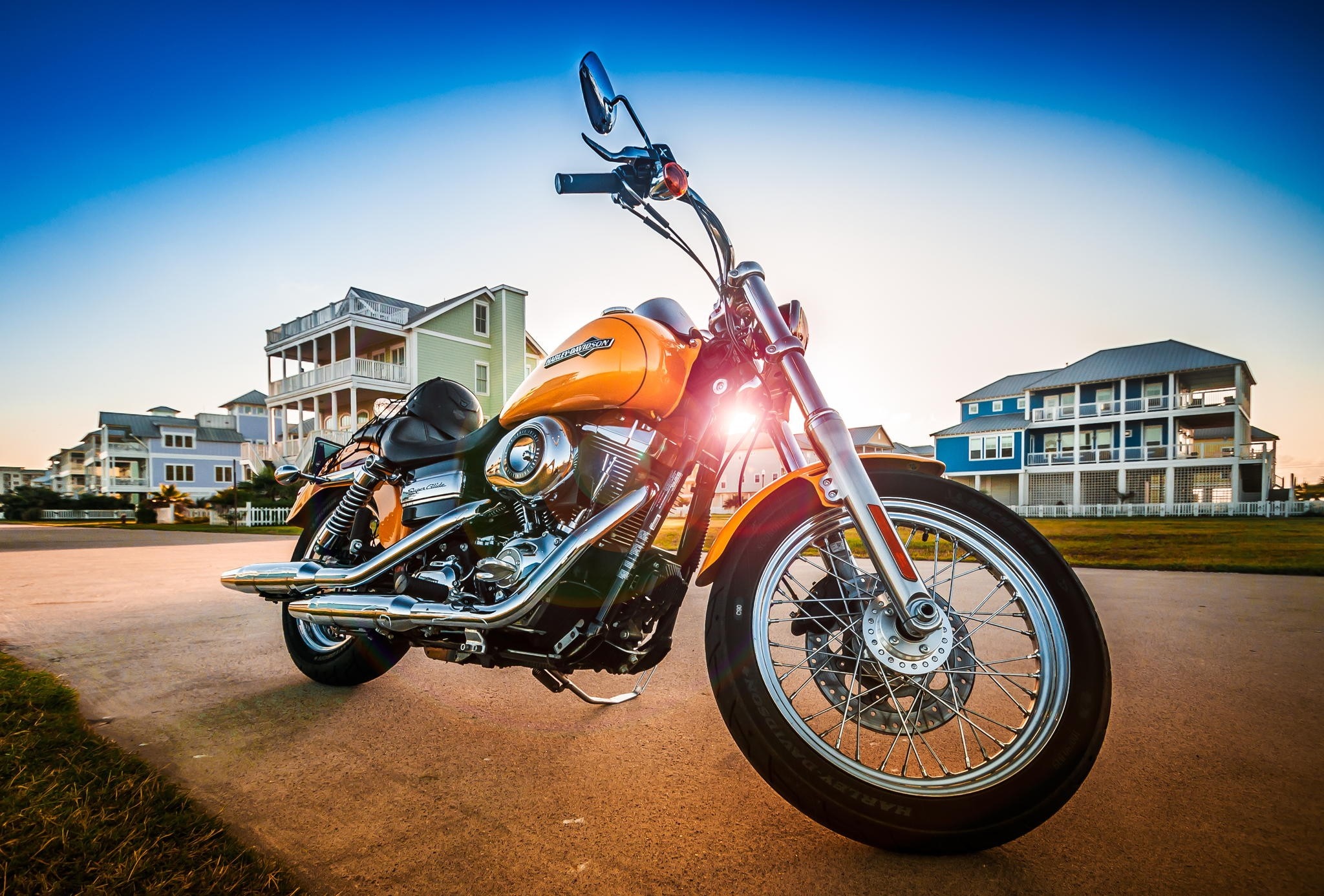 Orange Harley Davidson motorcycle parked by beach houses HD Wallpaper