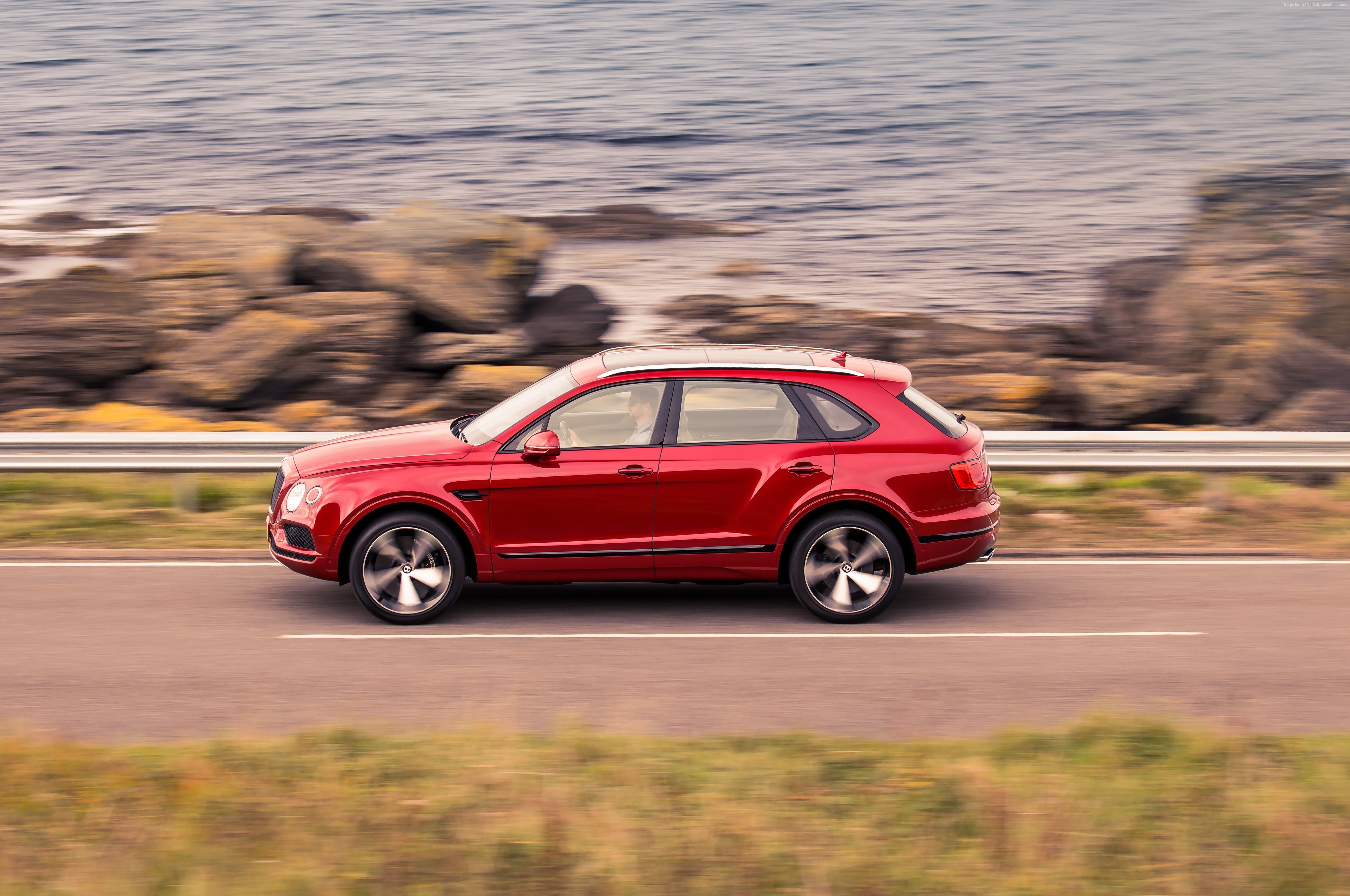 Red Bentley Bentayga V8 driving on coastal road HD Wallpaper
