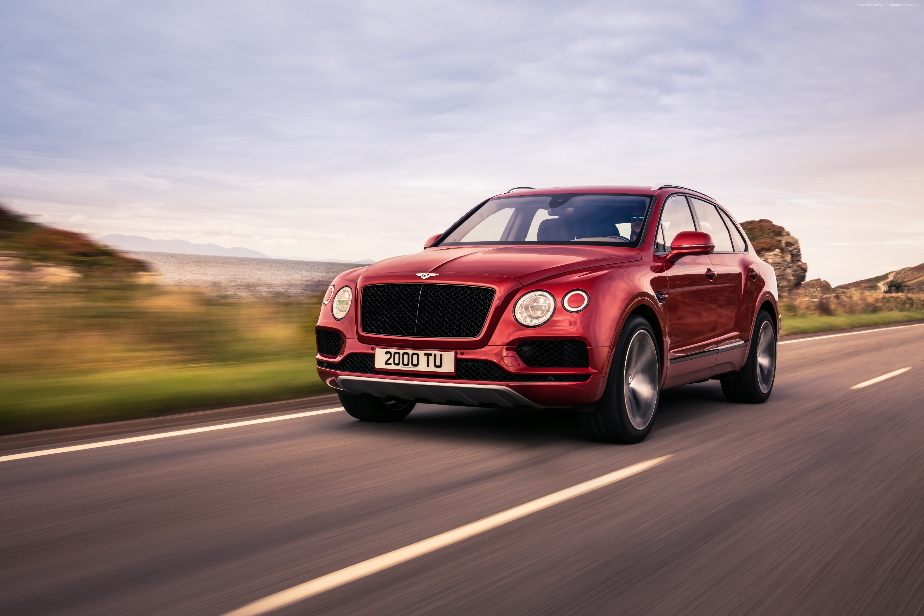 Red Bentley Bentayga V8 driving on a coastal road HD Wallpaper