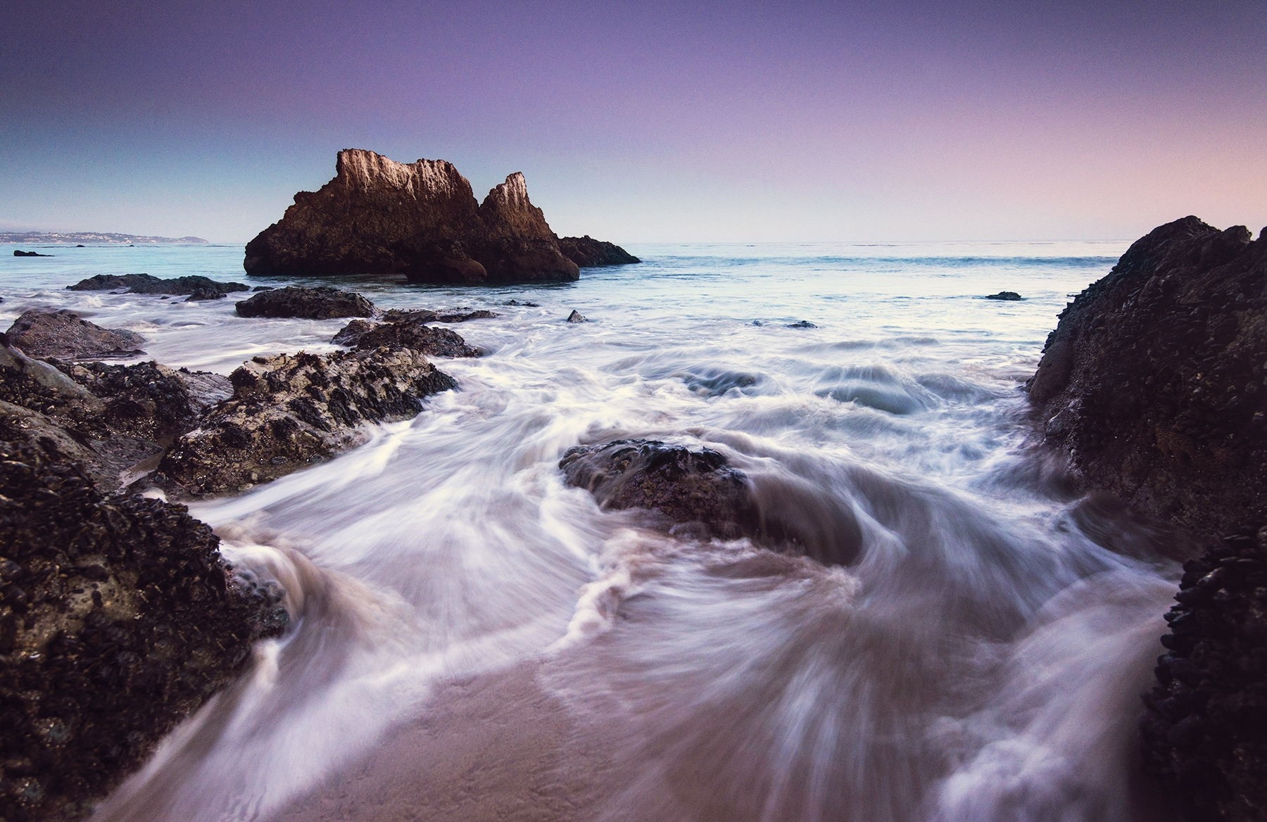 Ocean waves crashing on rocky shore at sunset HD Wallpaper