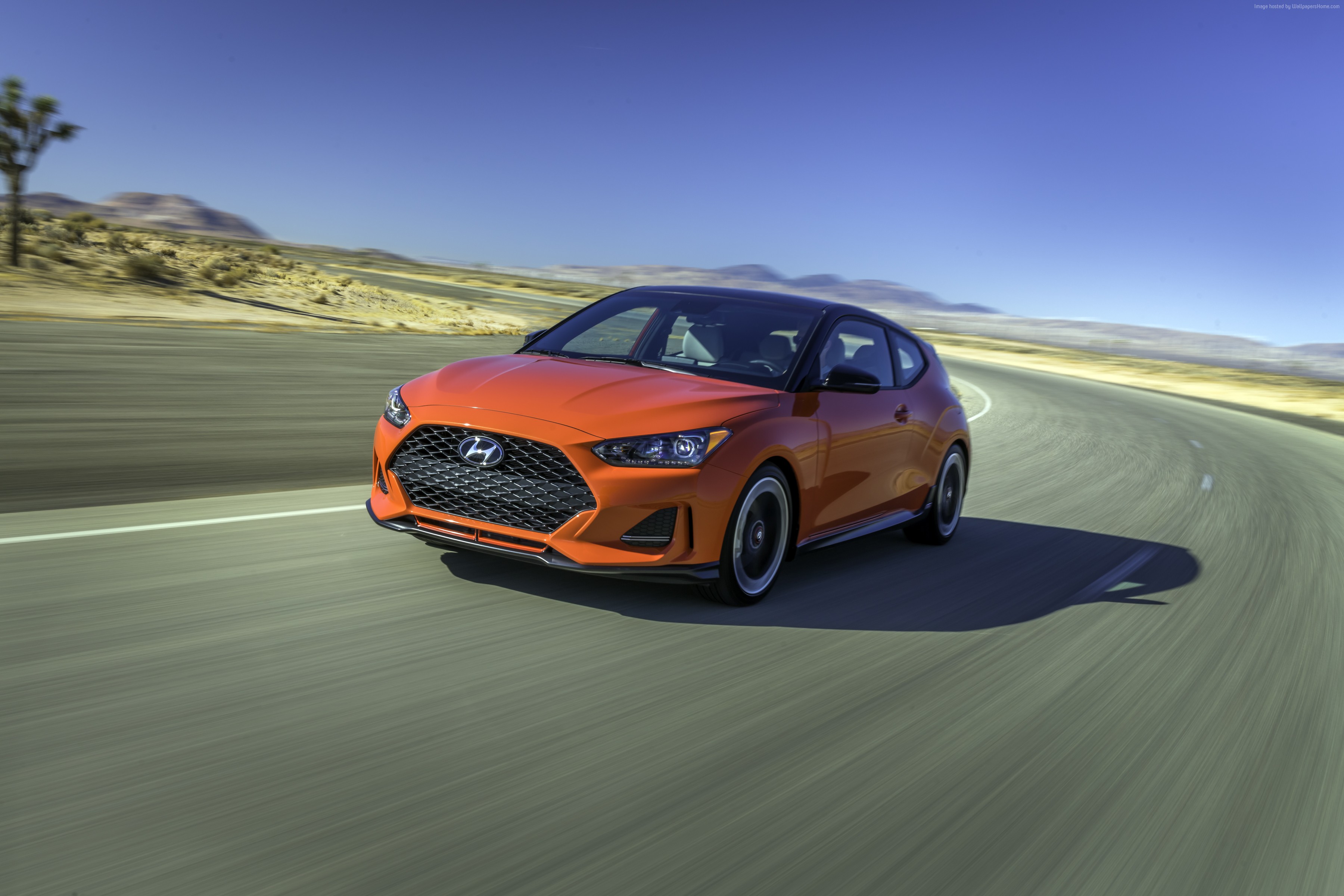 Orange Hyundai Veloster driving on desert road HD Wallpaper