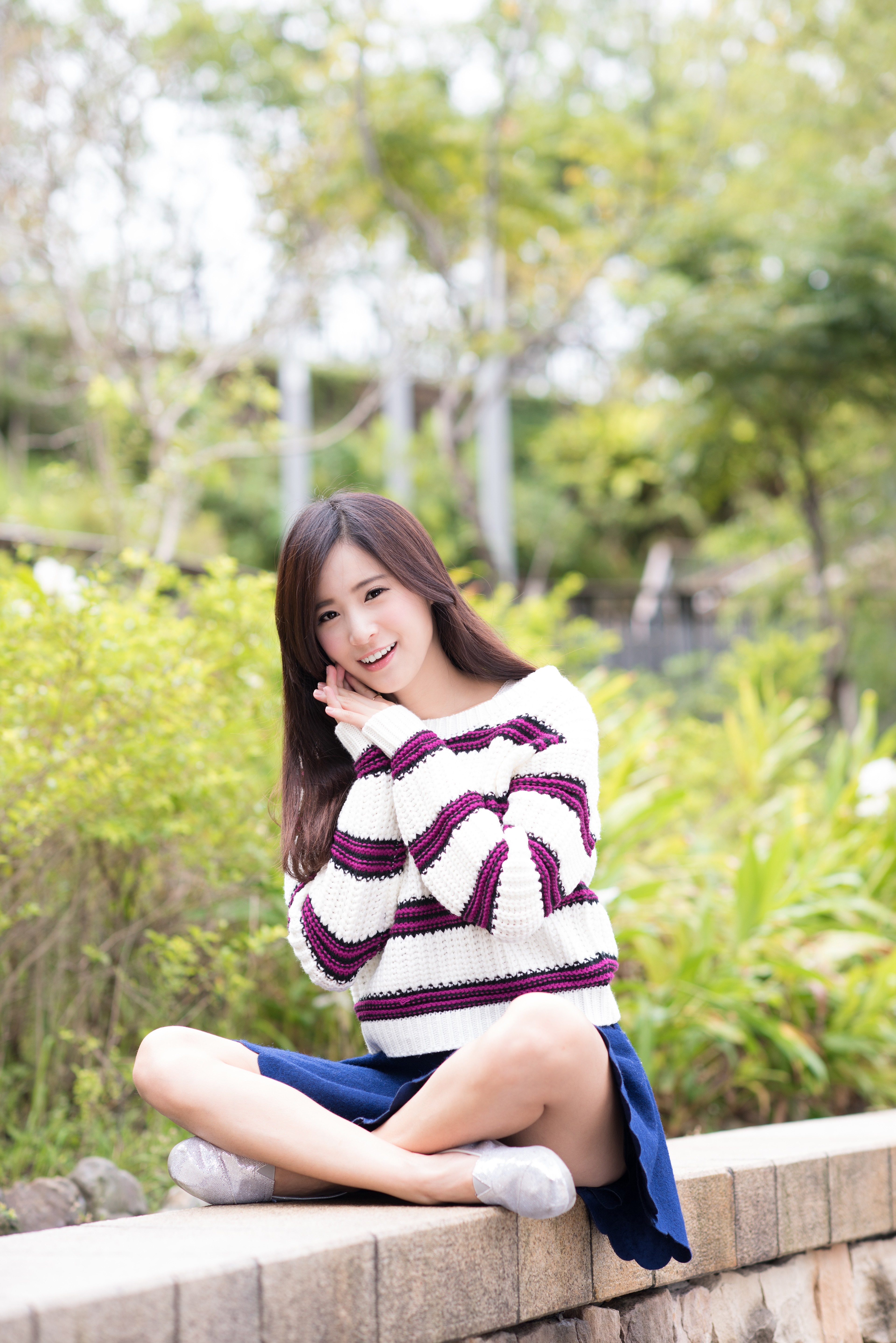 Asian woman sitting outdoors wearing a striped sweater HD Wallpaper
