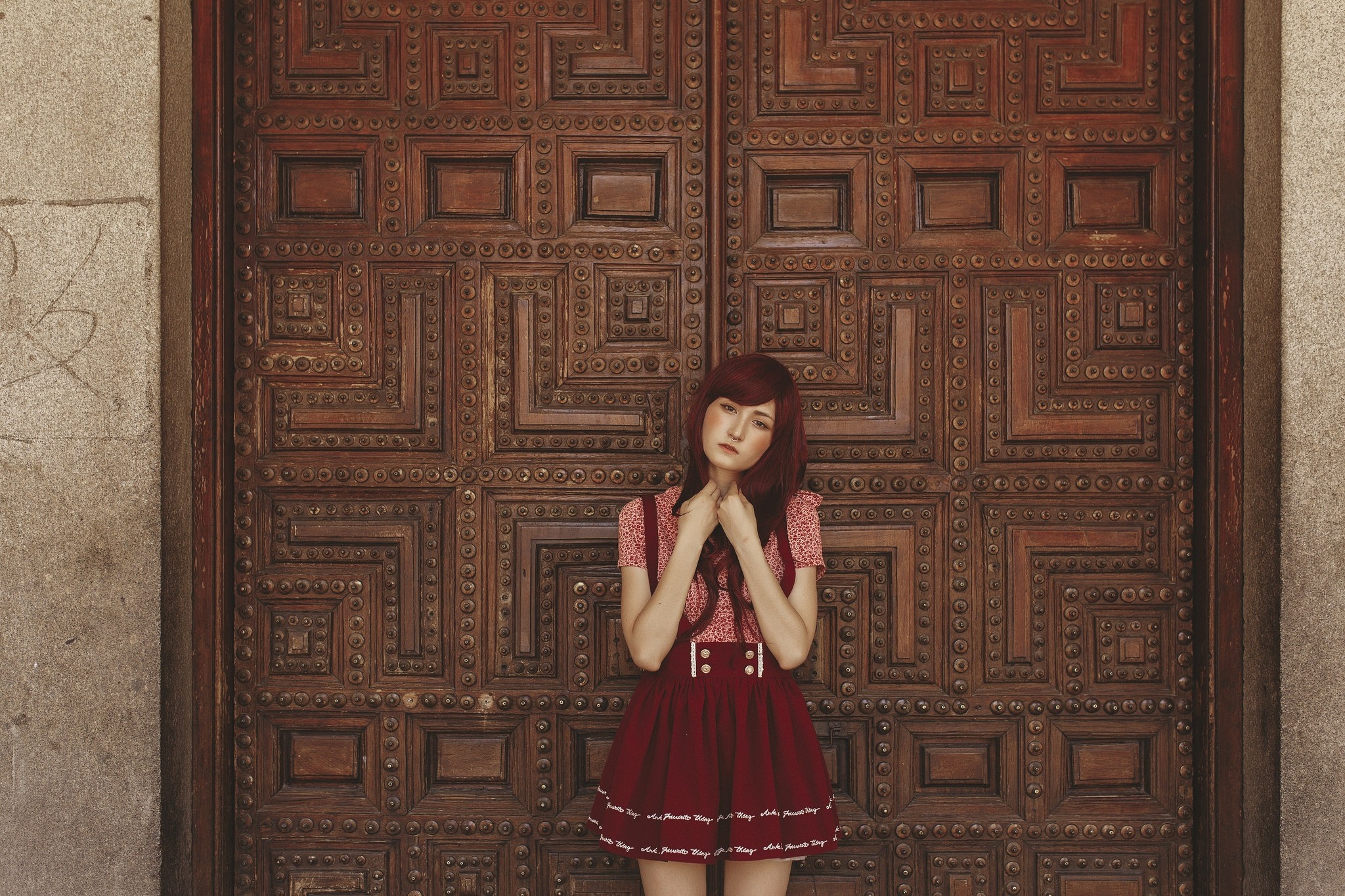 Woman in red dress standing in front of a wooden door HD Wallpaper