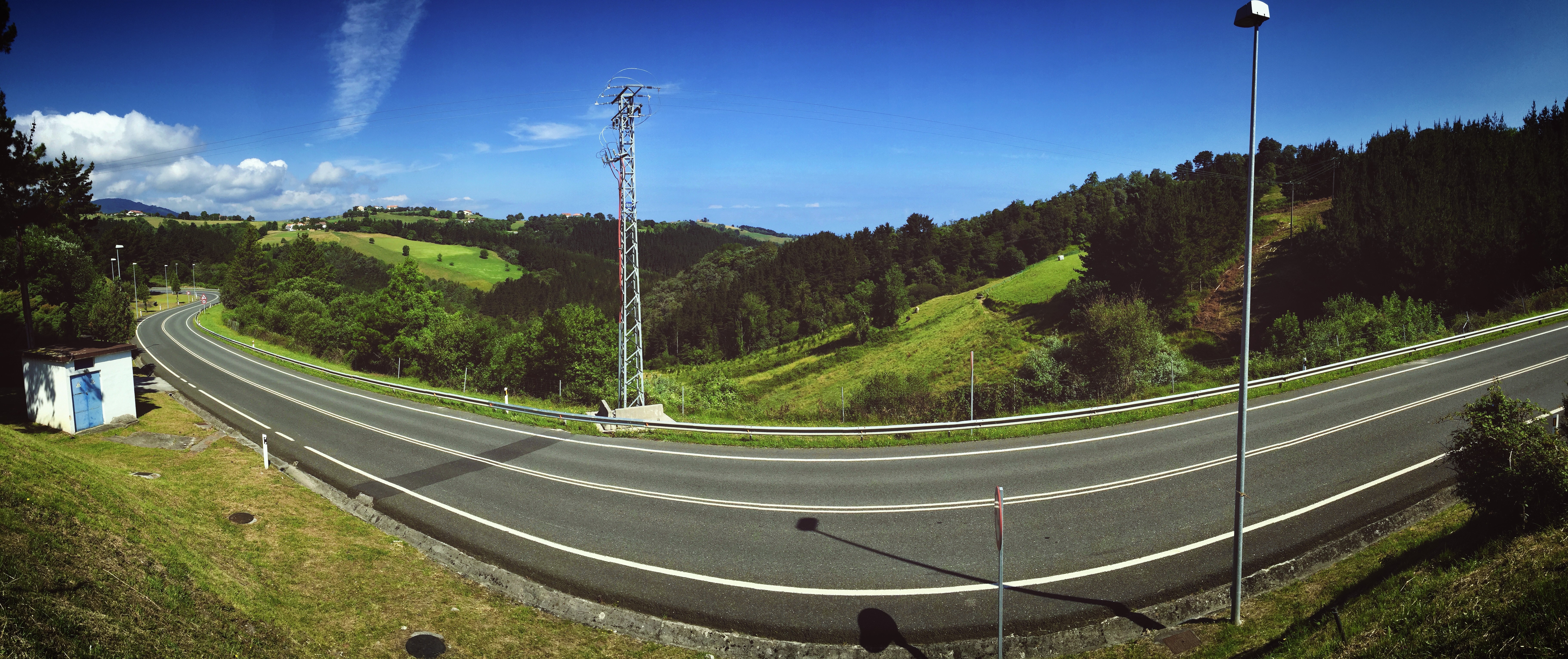 Panoramic view of a winding road through green hills in Spain HD Wallpaper