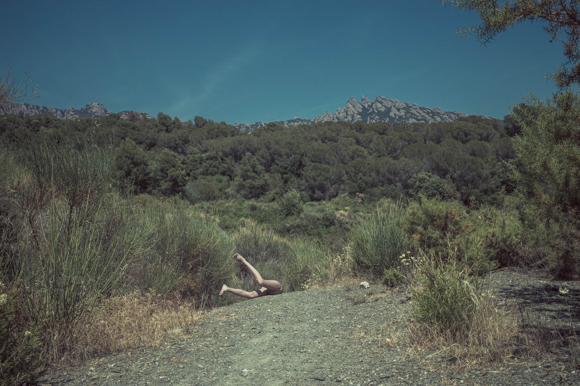 Person lying on a rocky path in a forest landscape HD Wallpaper