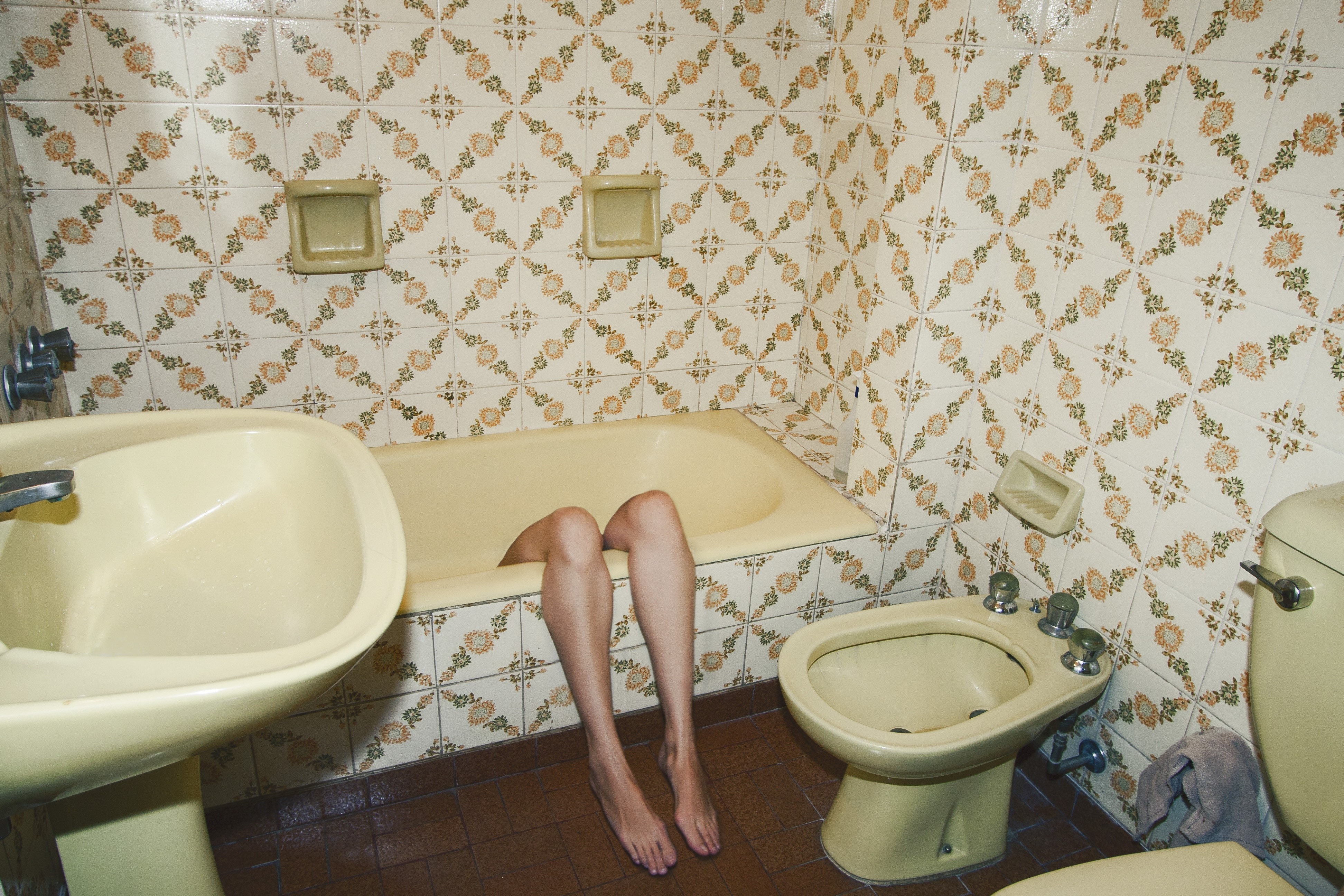 Legs in a bathtub in a tiled bathroom HD Wallpaper