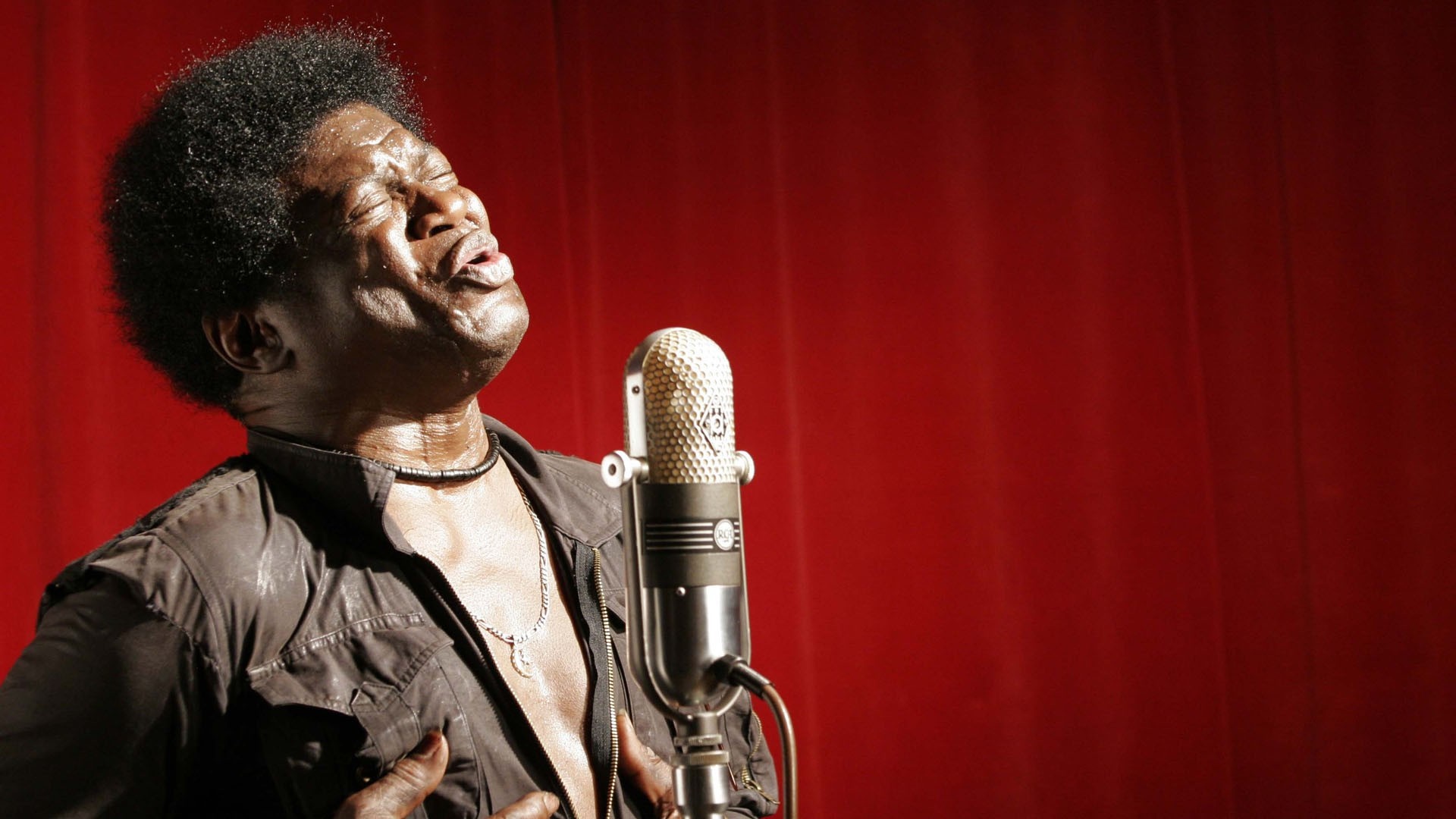 Charles Bradley singing into a vintage microphone on stage HD Wallpaper