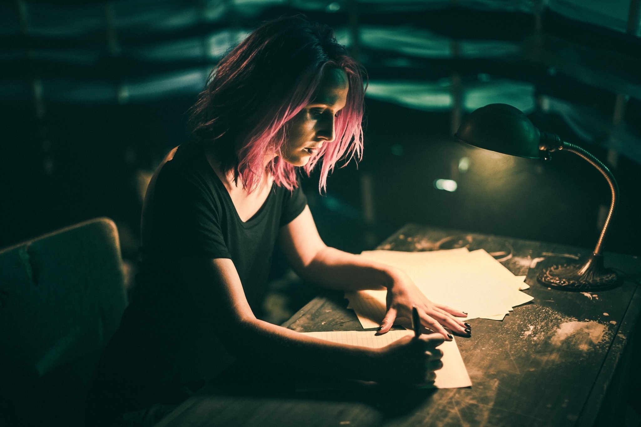 Woman with pink hair writing at a desk HD Wallpaper
