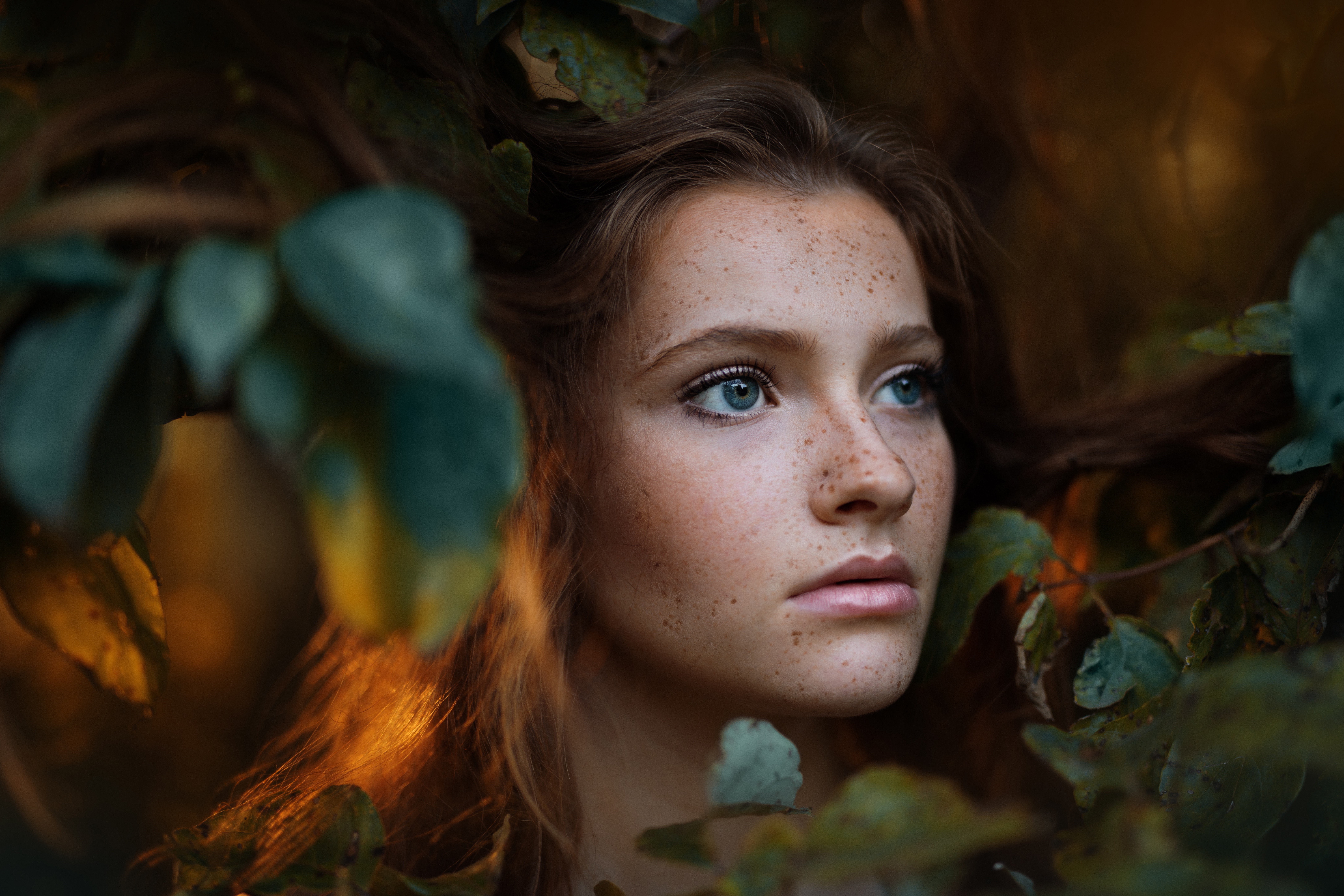 Young woman with freckles surrounded by leaves HD Wallpaper