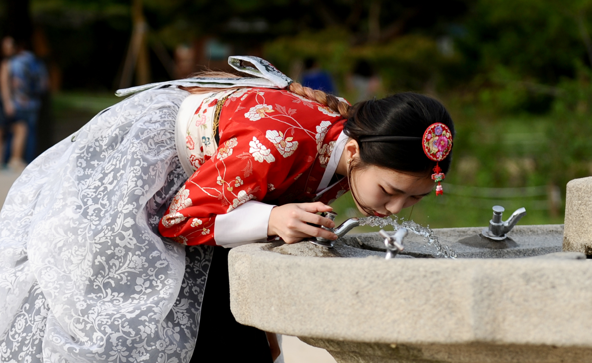 Woman in Hanbok drinking water from a fountain HD Wallpaper