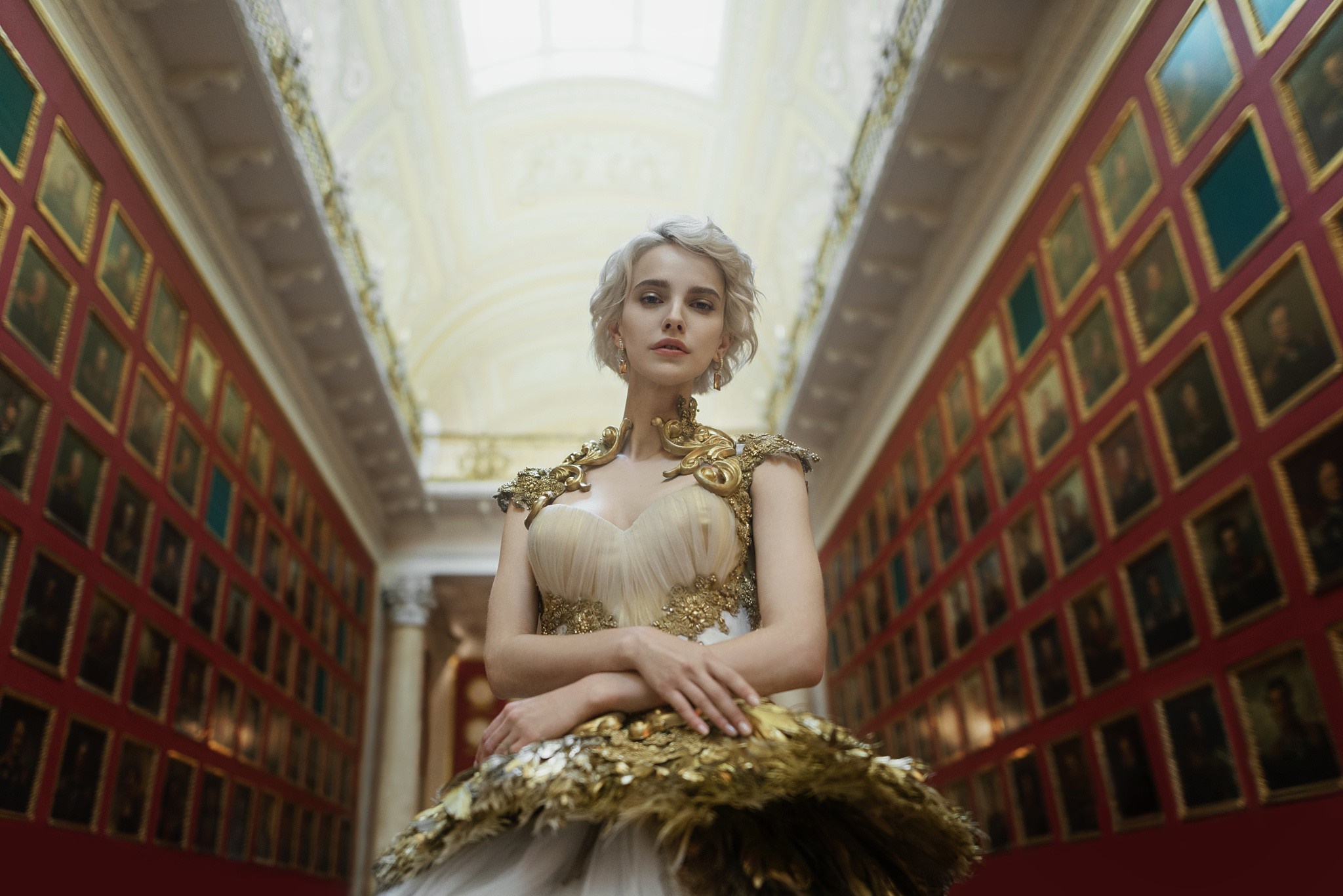 Woman in ornate gold and white gown in art gallery HD Wallpaper