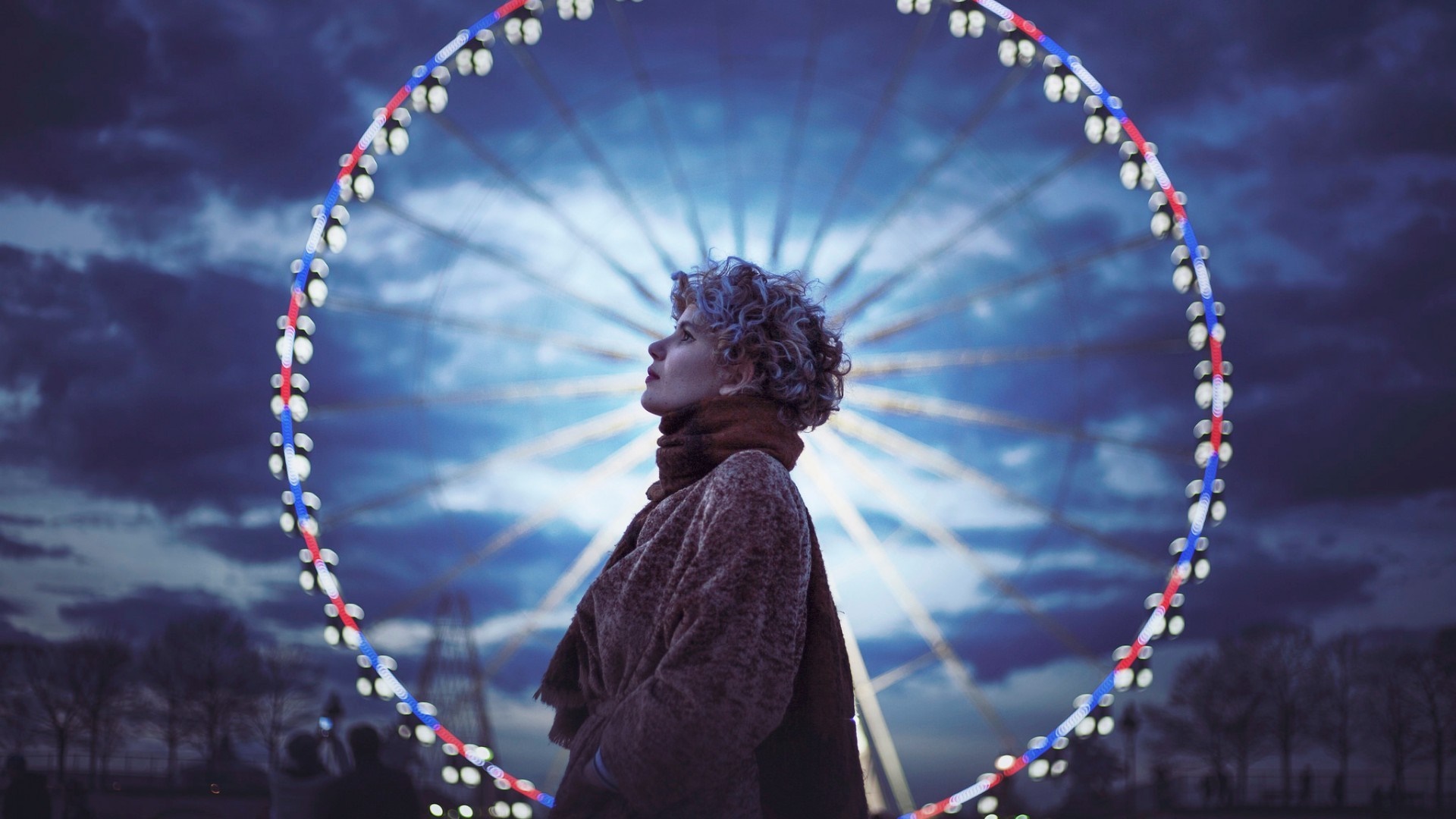 Woman looking up at a Ferris wheel at night HD Wallpaper