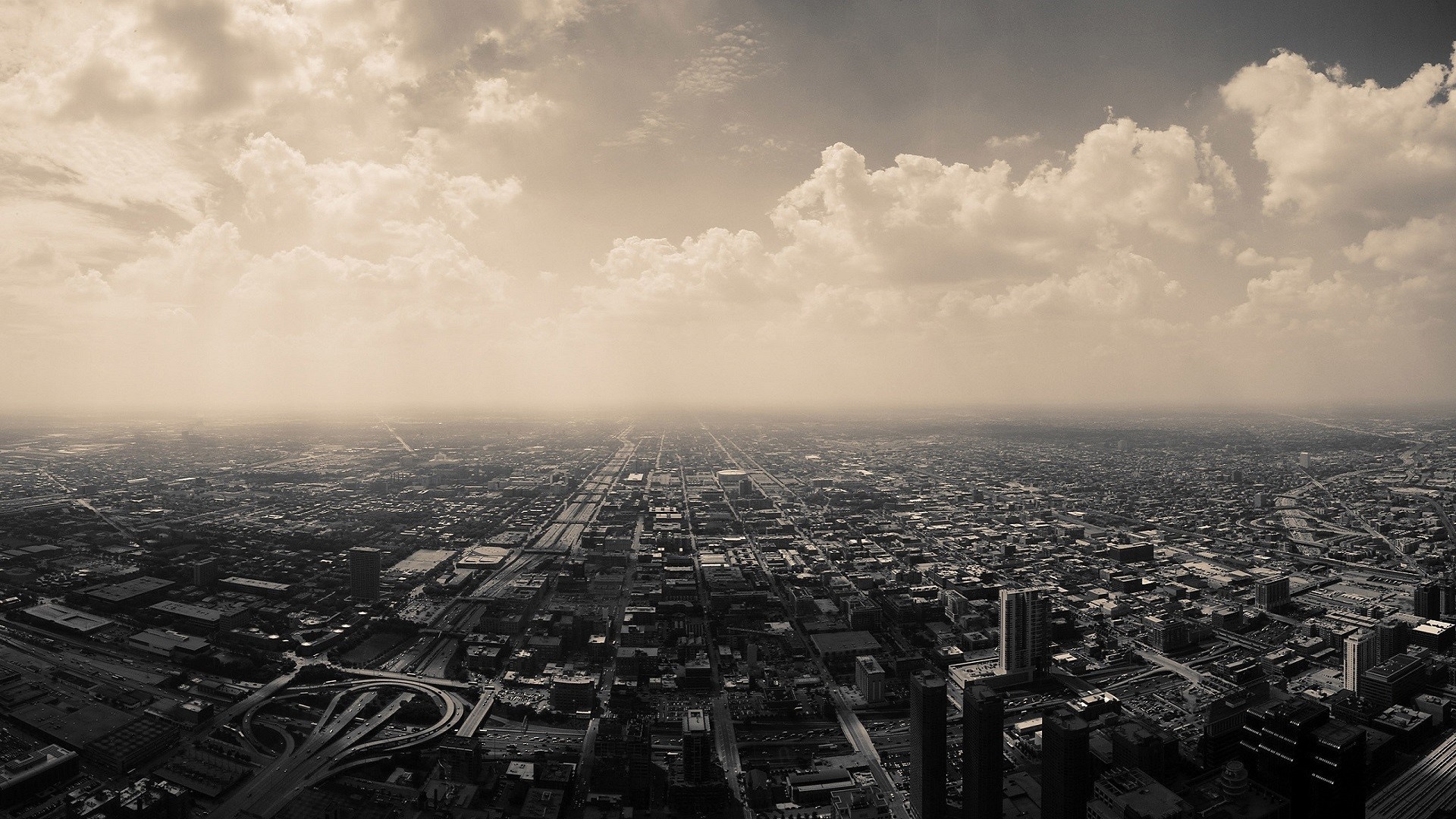 Aerial view of a sprawling cityscape under a cloudy sky HD Wallpaper