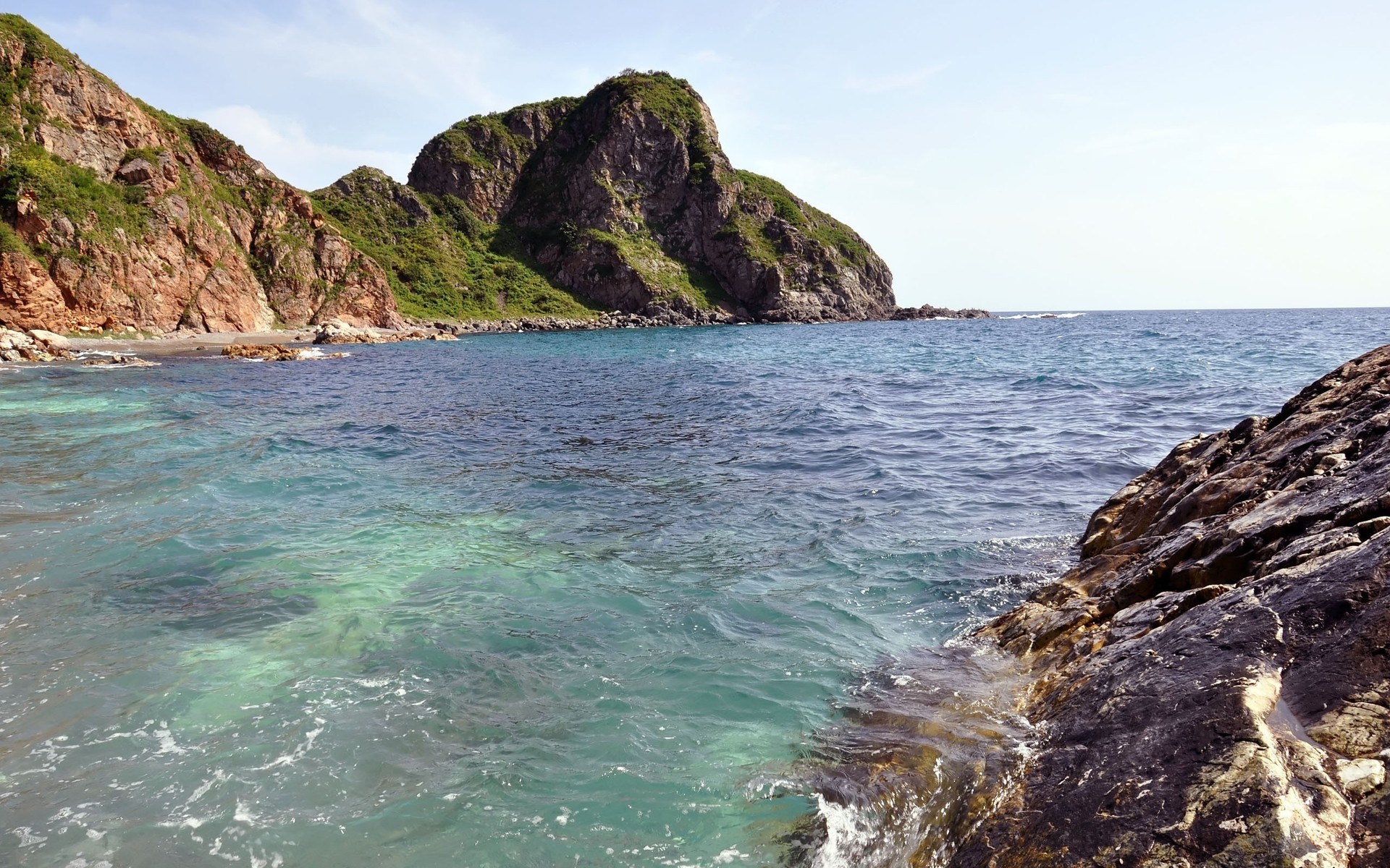 Rocky coastline with clear blue ocean water HD Wallpaper