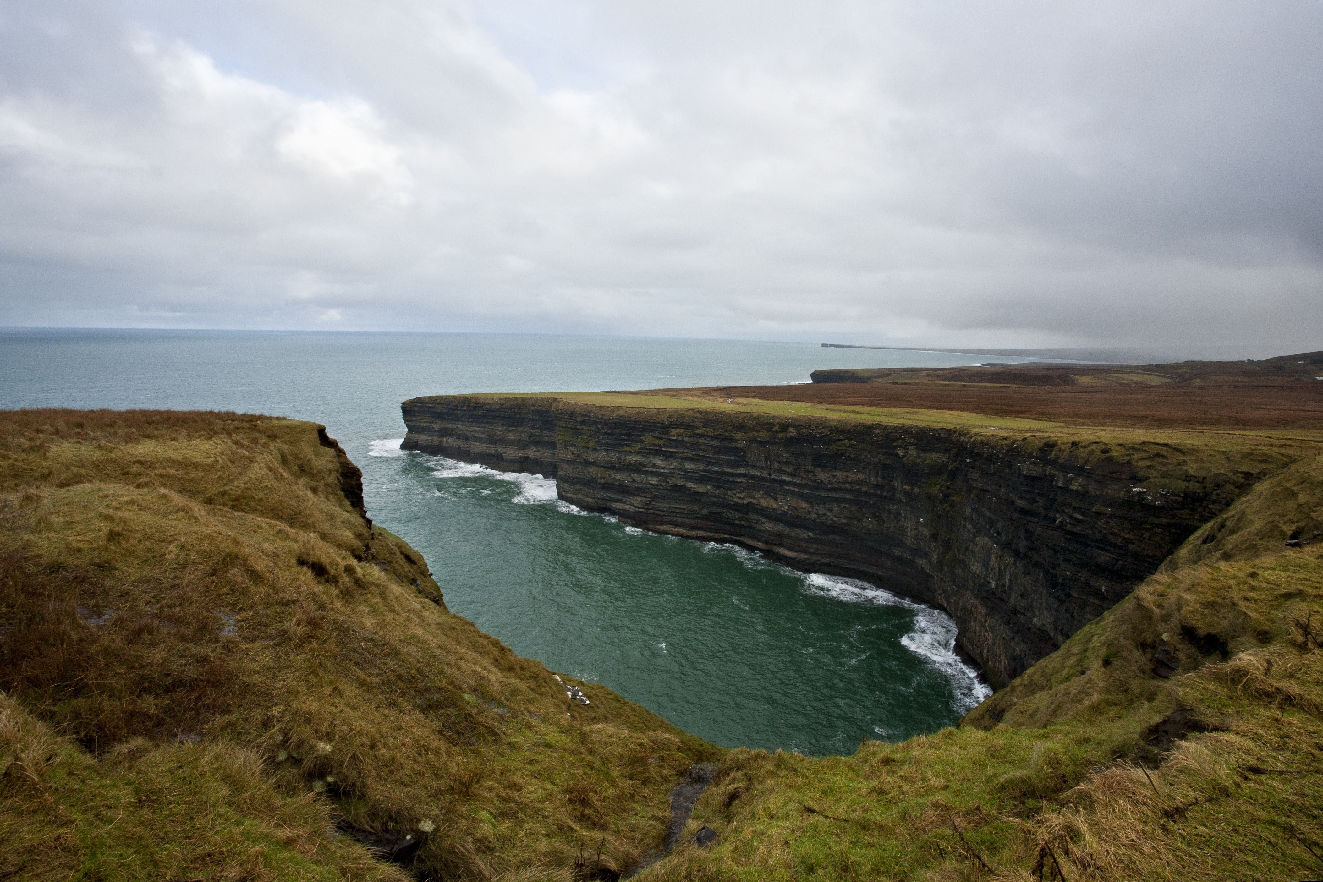Dramatic cliffs overlooking the ocean on a cloudy day HD Wallpaper