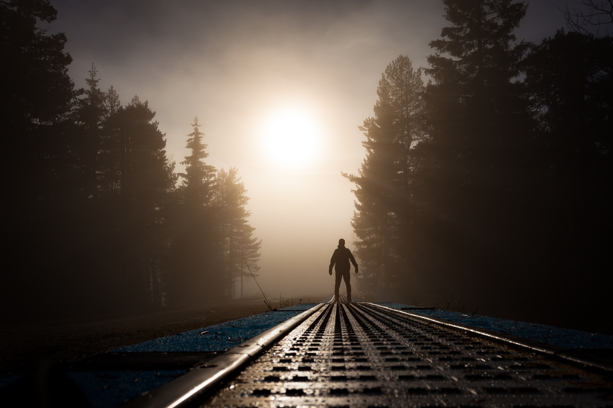 Man standing on train tracks in foggy forest at sunrise HD Wallpaper