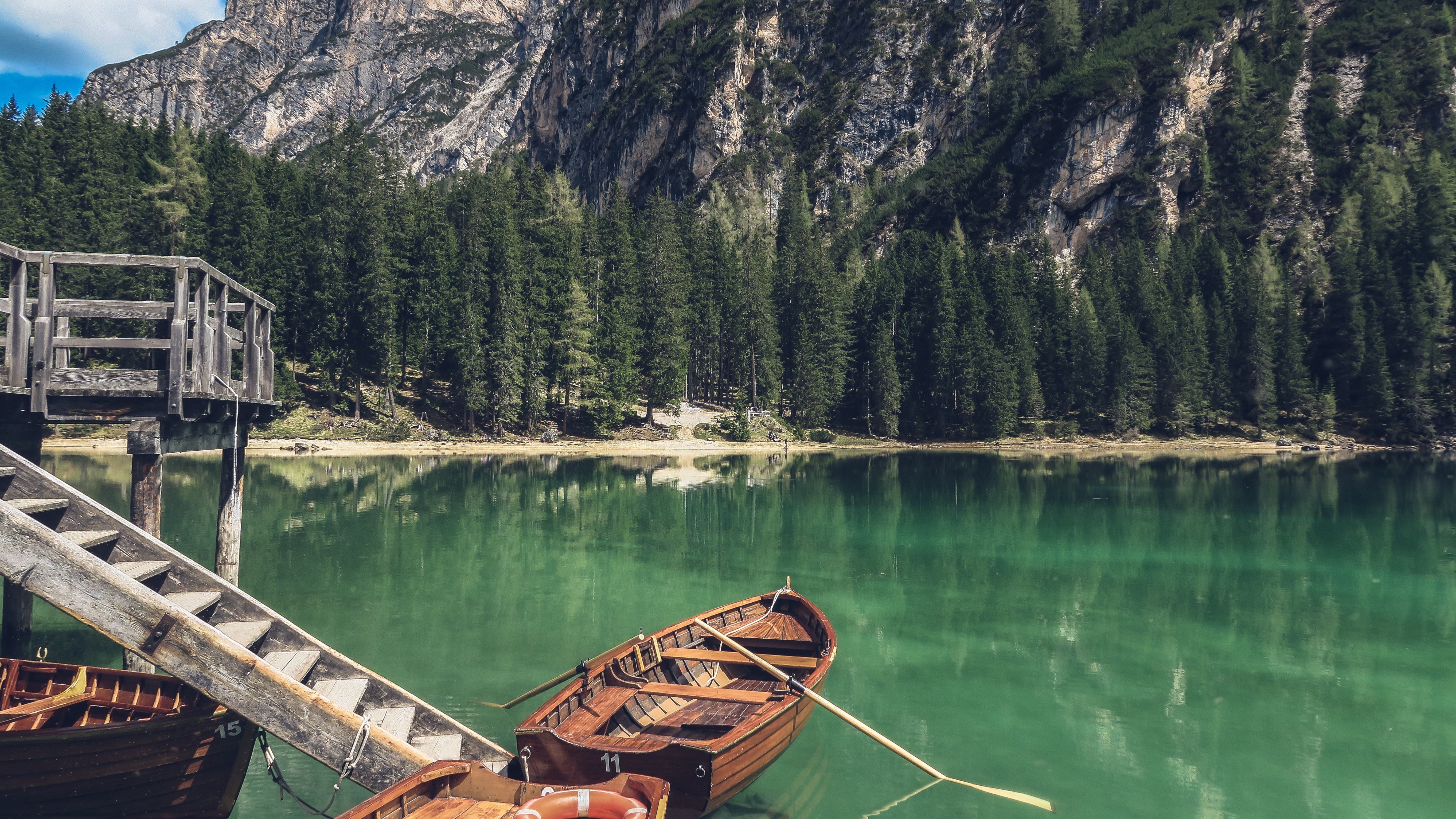 Wooden boats on a clear lake with mountains and trees HD Wallpaper