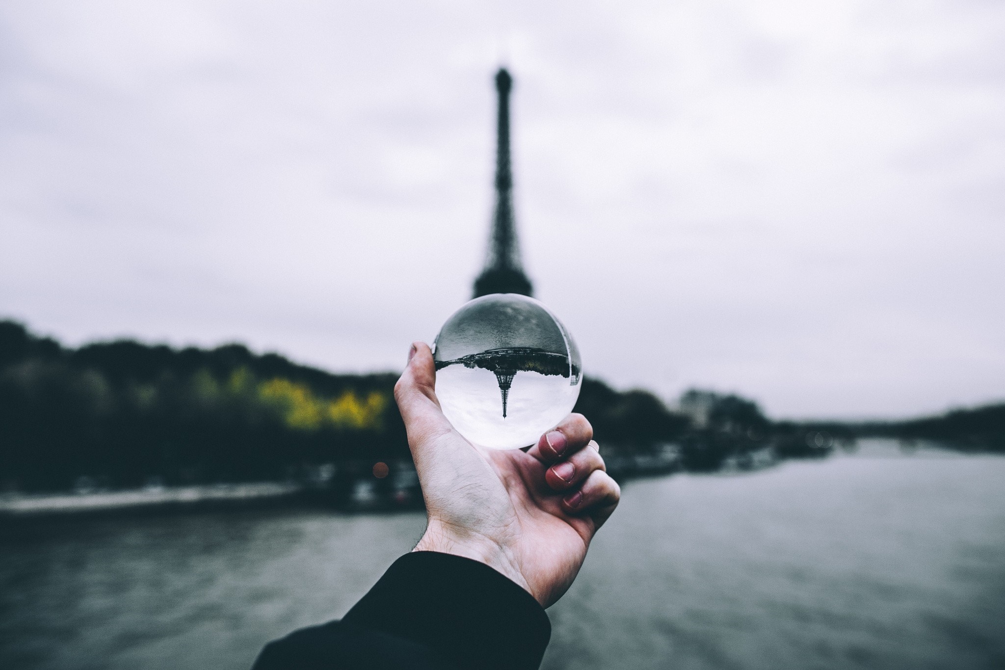 Eiffel Tower reflected in a crystal ball held by a hand HD Wallpaper