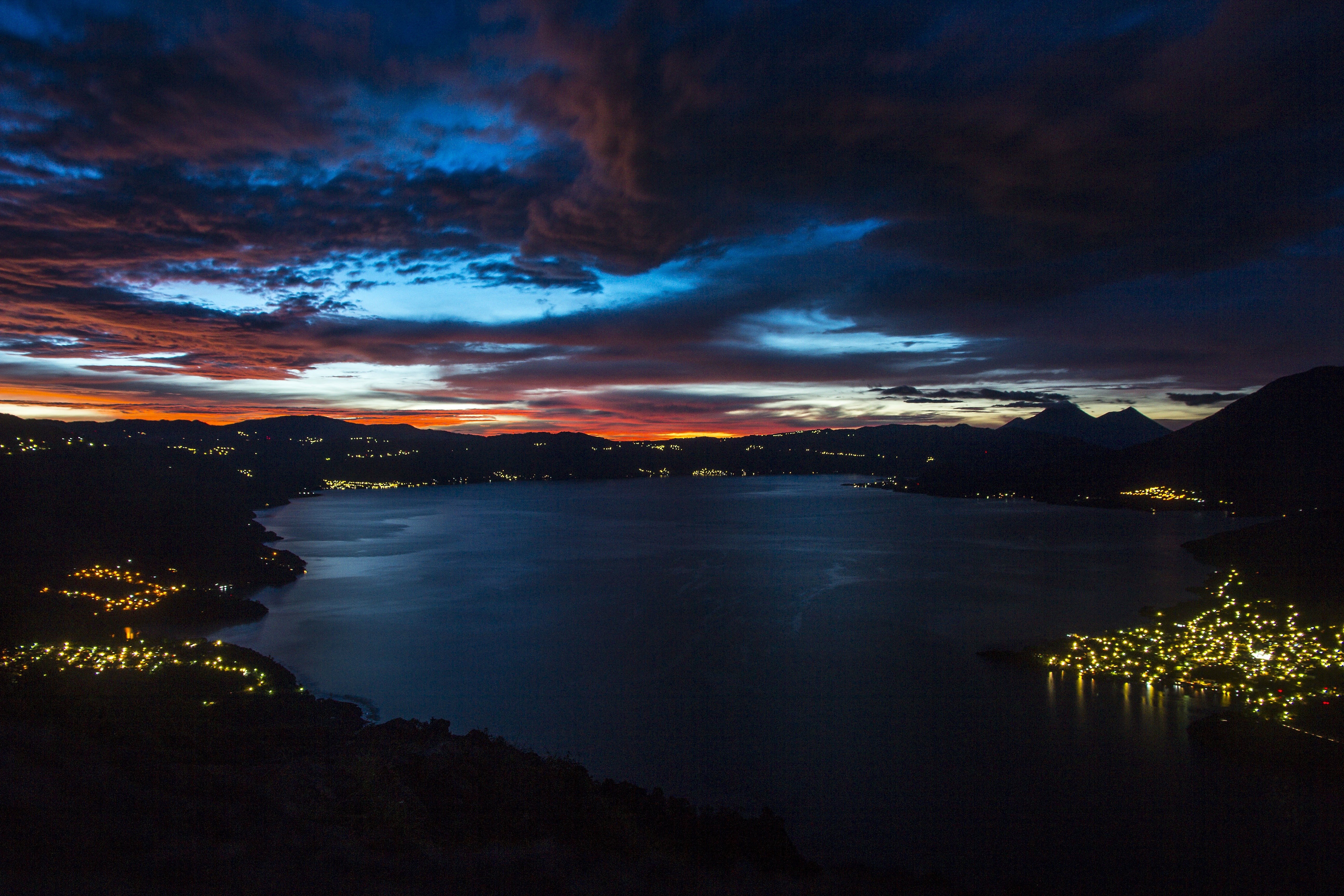 Lake and mountains at dusk with city lights HD Wallpaper