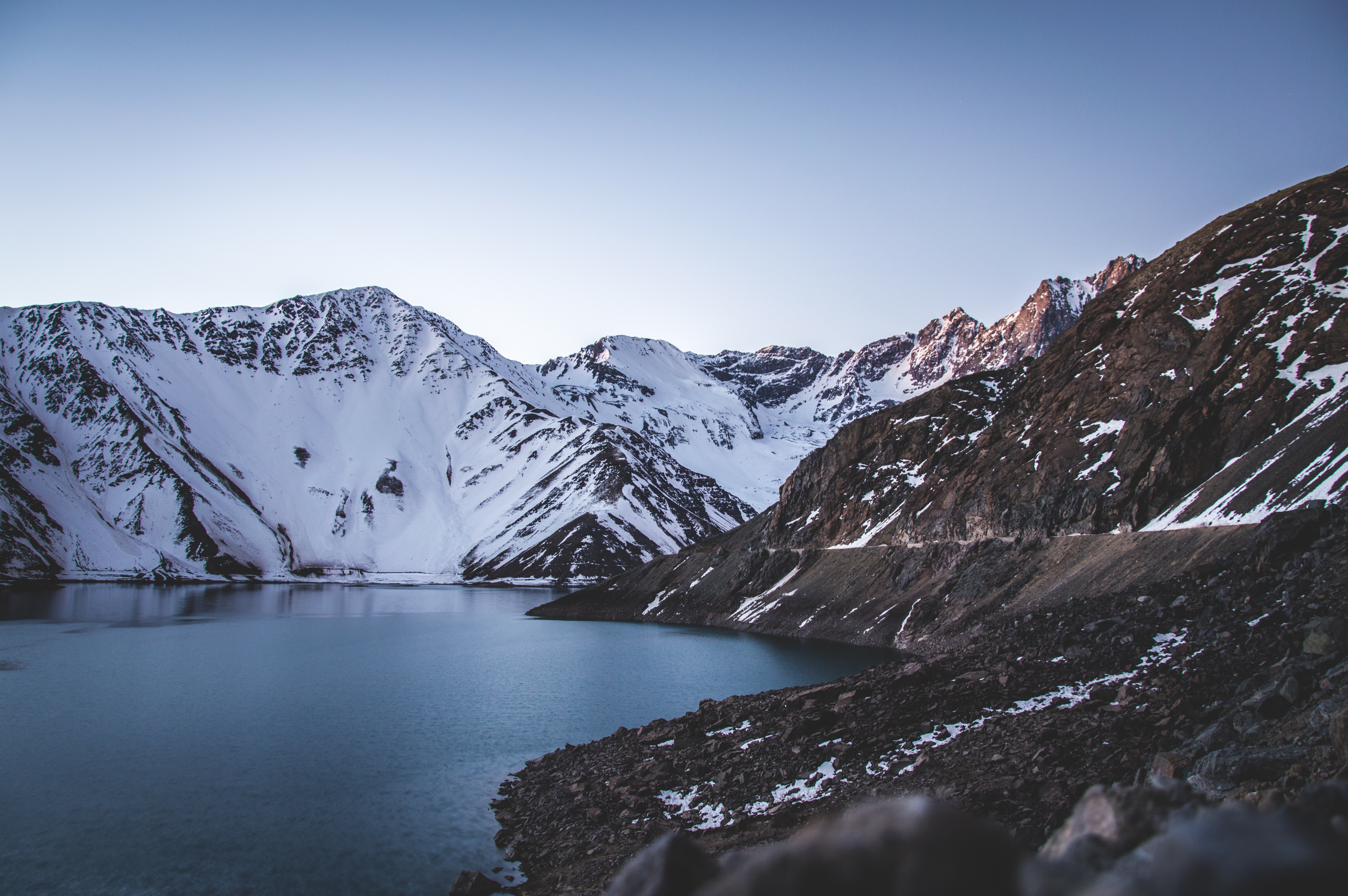 Snow-capped mountains overlooking a serene lake HD Wallpaper